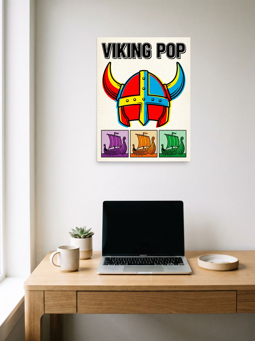 A 18x24 inch unframed paper Pop art print of 'Viking Pop' hanging above a worktable with a laptop.