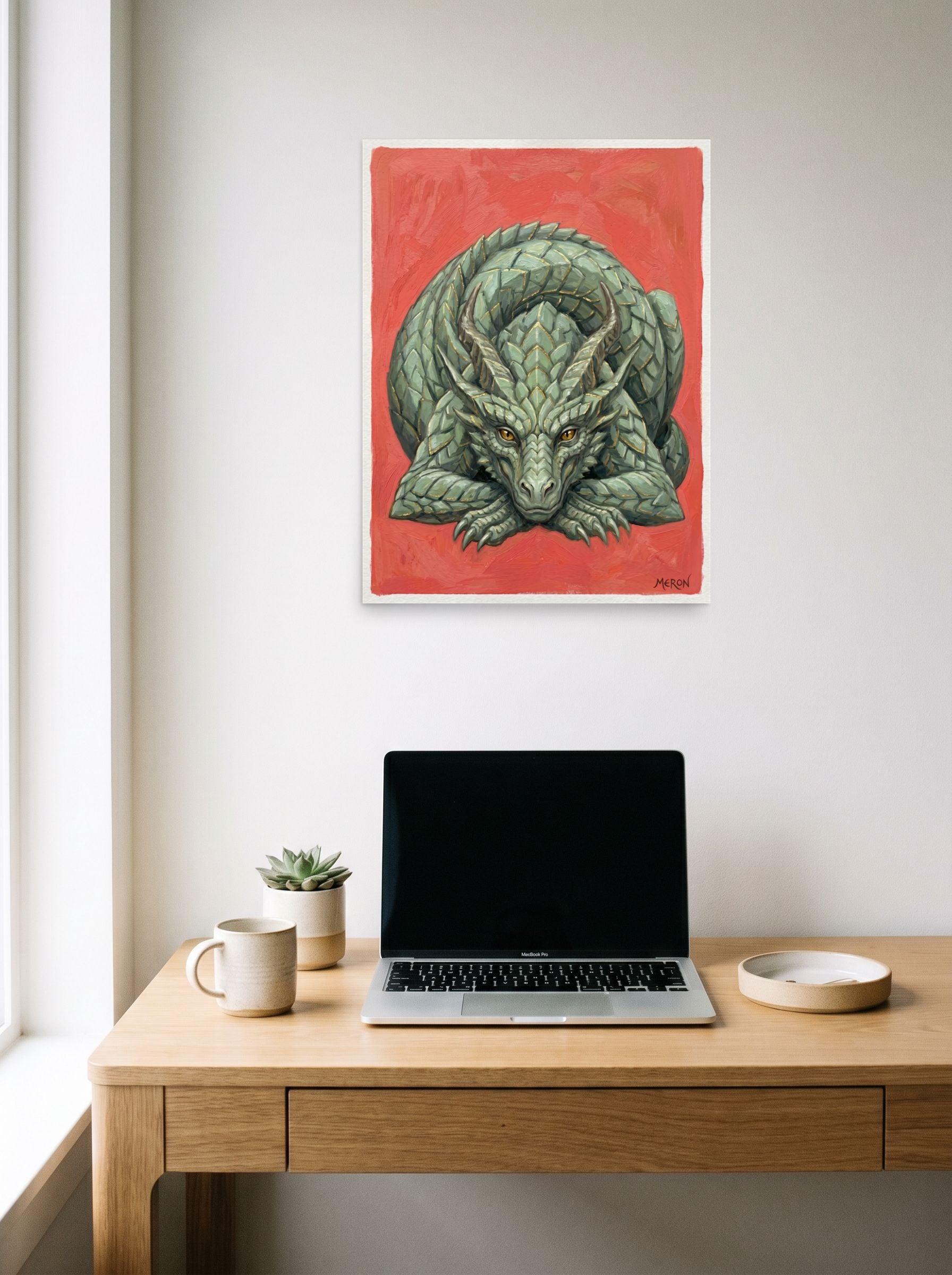 A 18x24 inch unframed paper Fantastic realism print of 'Slumbering Drake' hanging above a worktable with a laptop.