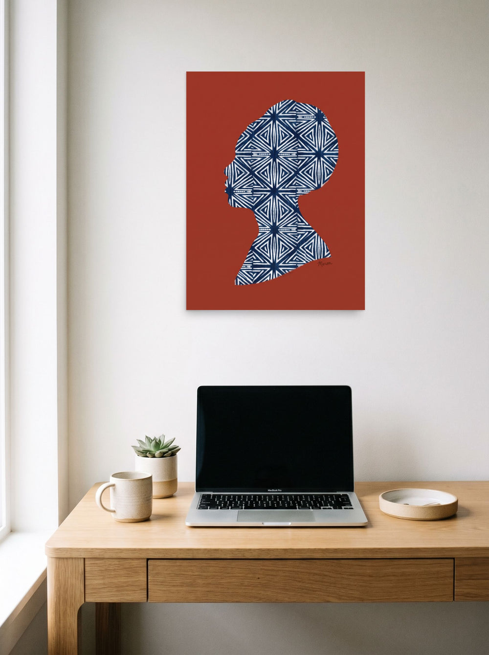 A 18x24 inch unframed paper Figurative art,Minimalism print of 'Indigo Heritage' hanging above a worktable with a laptop.