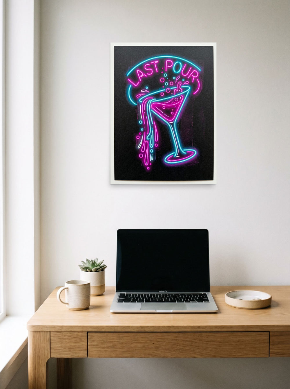 A 18x24 inch unframed paper Pop art print of 'Last Pour' hanging above a worktable with a laptop.