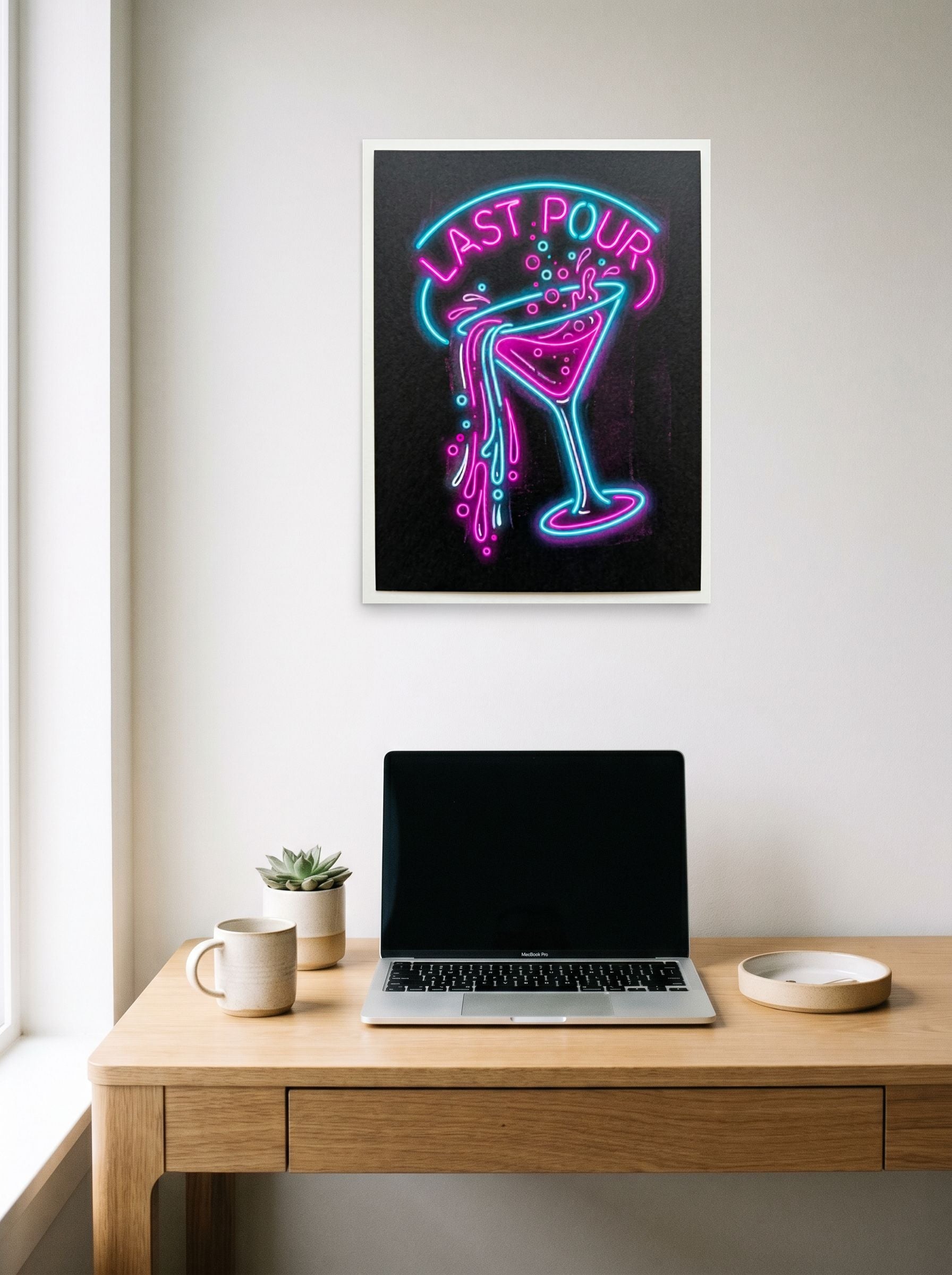 A 18x24 inch unframed paper Pop art print of 'Last Pour' hanging above a worktable with a laptop.