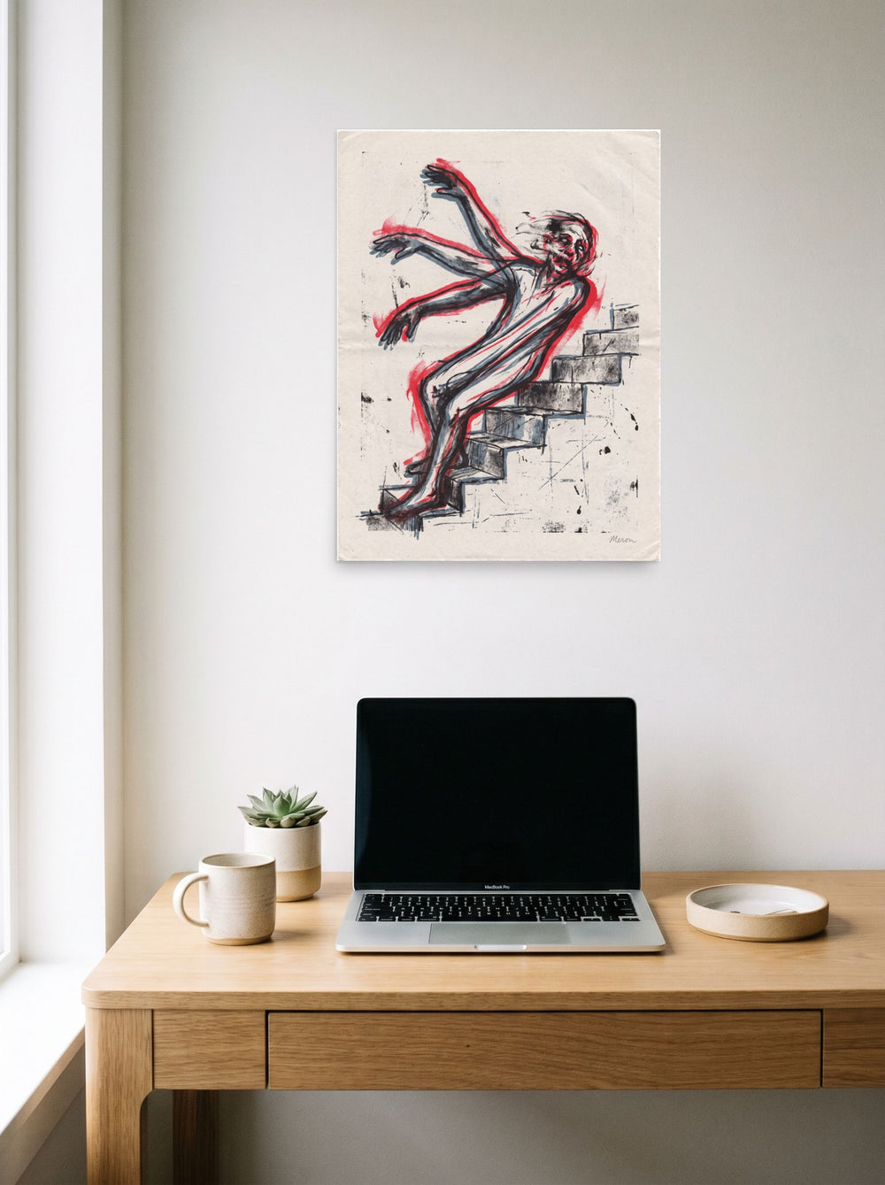 A unframed paper print of the Expressionism artwork 'Descent in Motion', hanging above a worktable with a laptop.