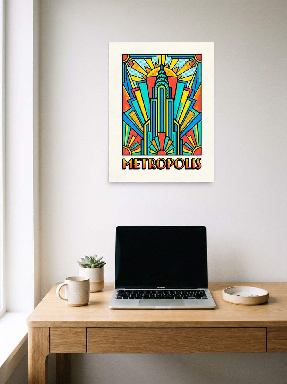 A 18x24 inch unframed paper Pop art print of 'Metropolis Deco' hanging above a worktable with a laptop.