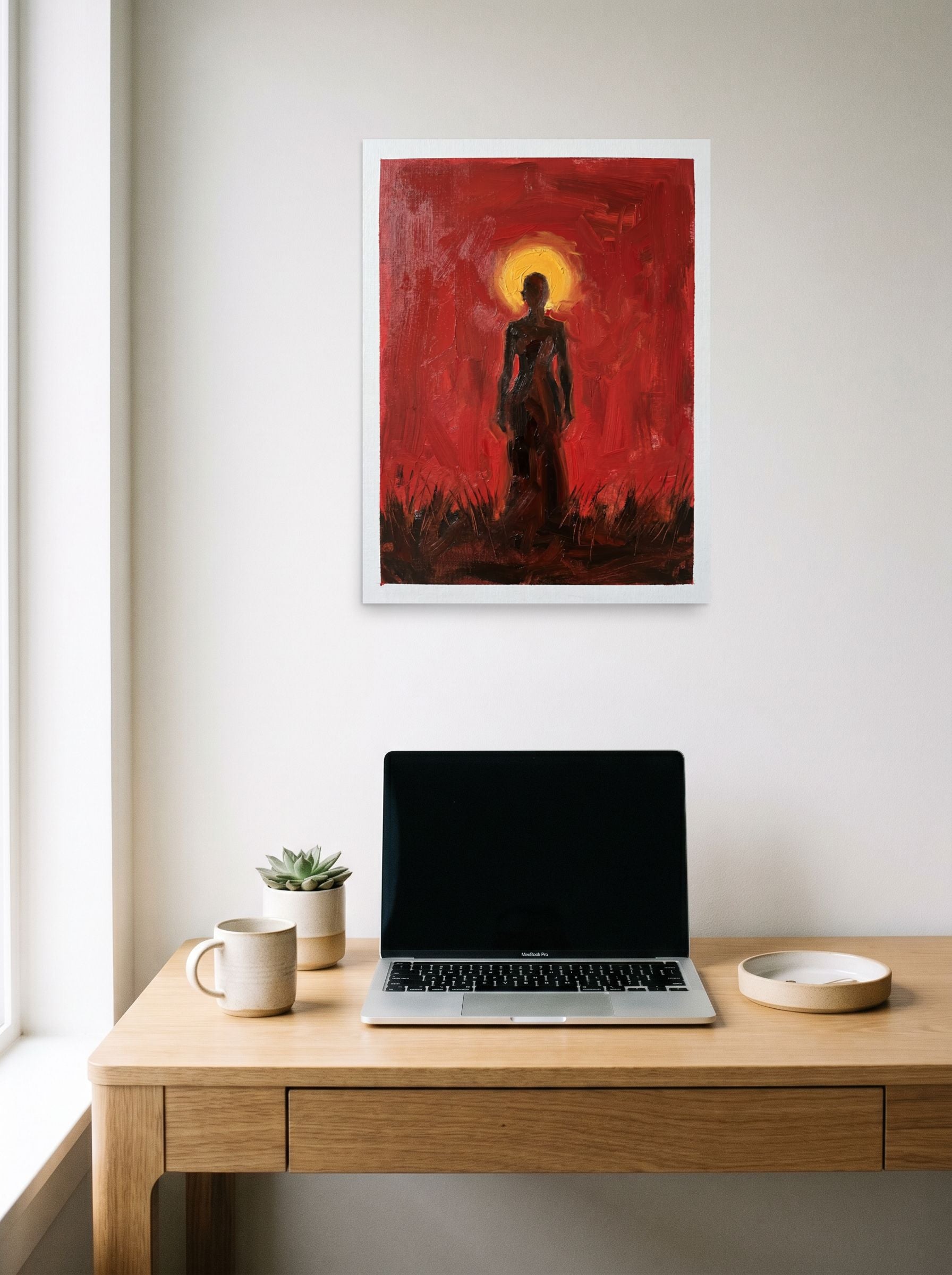 A 18x24 inch unframed paper Expressionism print of 'Crimson Halo' hanging above a worktable with a laptop.