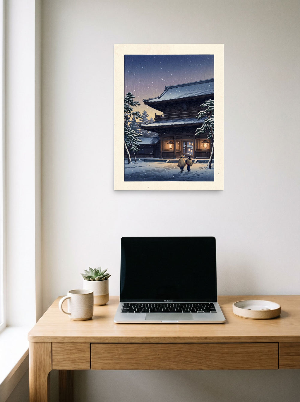 A 18x24 inch unframed paper Shin hanga print of 'Snowfall at Dusk' hanging above a worktable with a laptop.