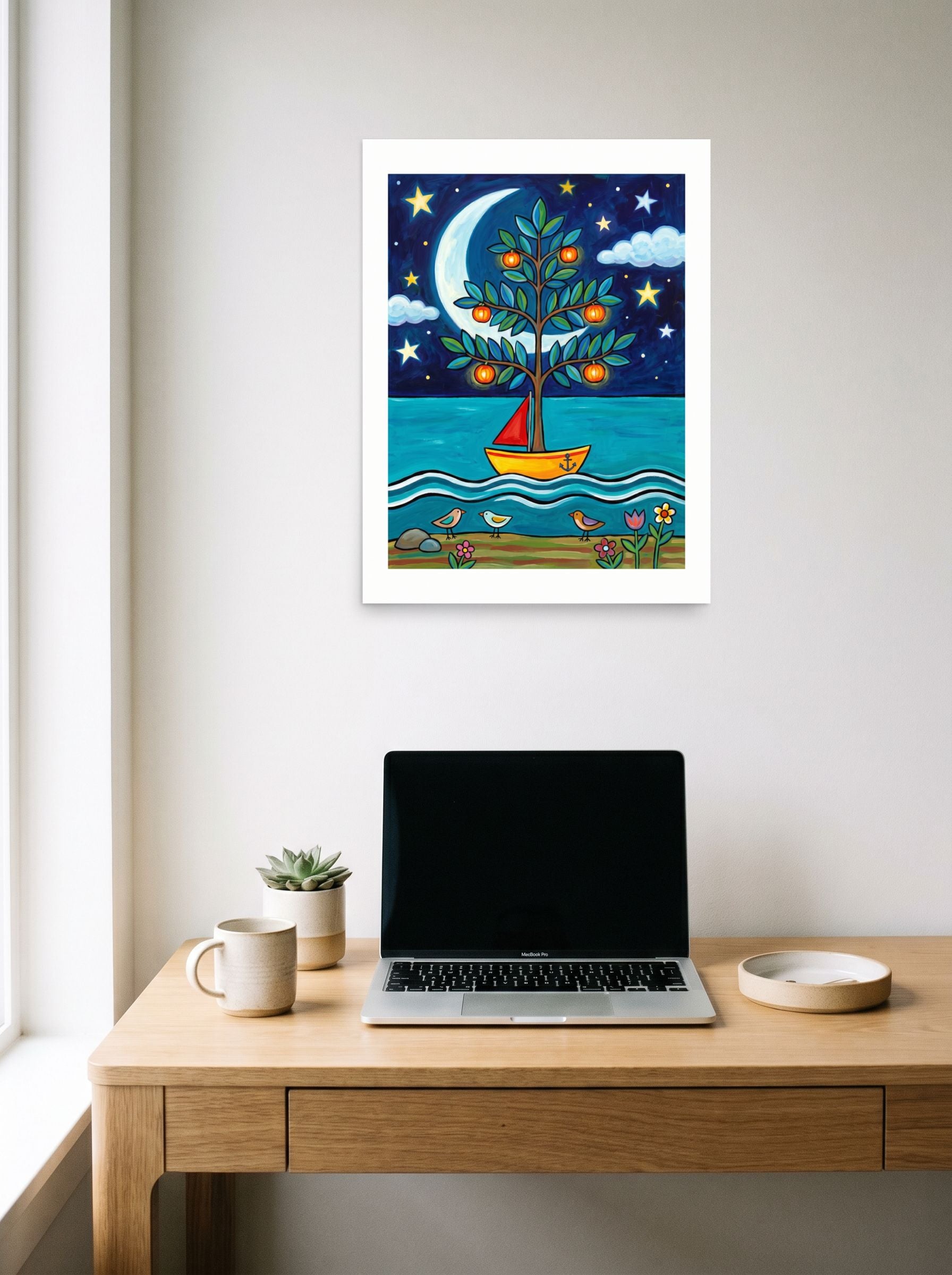 A 18x24 inch unframed paper Naive art print of 'The Glowing Orchard Boat' hanging above a worktable with a laptop.