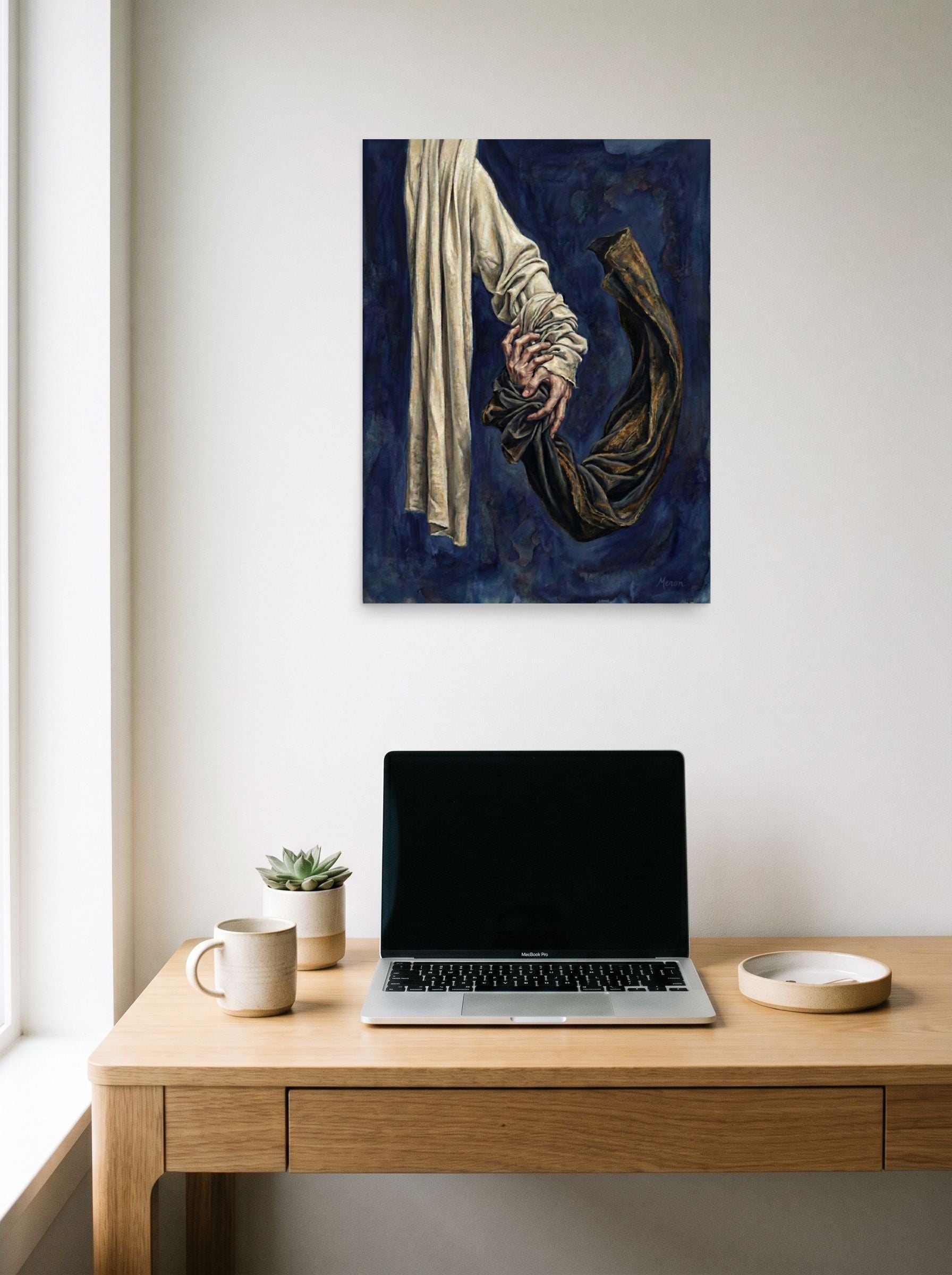 A 18x24 inch unframed paper Realism,Surrealism print of 'Tethered Grasp' hanging above a worktable with a laptop.