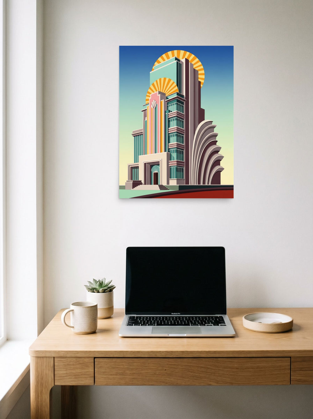 A 18x24 inch unframed paper Art Deco print of 'Deco Metropolis' hanging above a worktable with a laptop.
