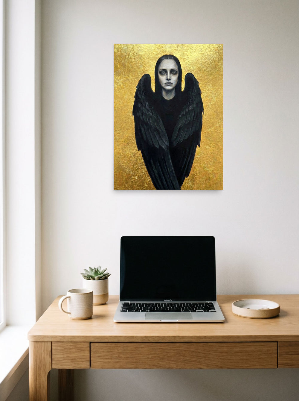 A 18x24 inch unframed paper Figurative art,Symbolism print of 'The Dark Seraph' hanging above a worktable with a laptop.