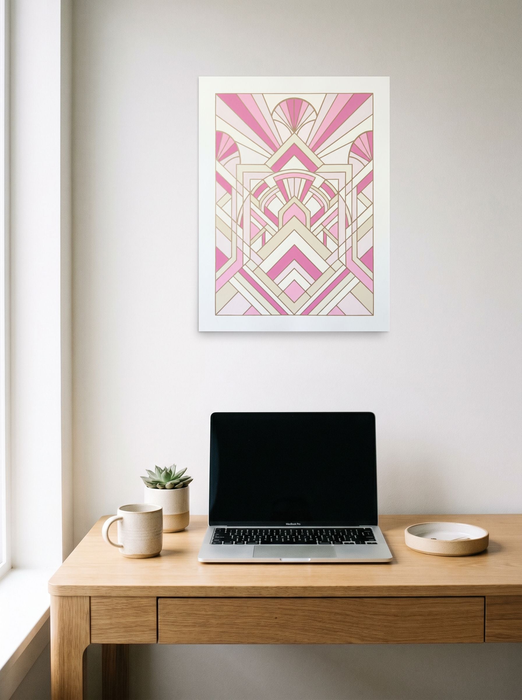 A 18x24 inch unframed paper Art Deco print of 'Rose Deco Radiance' hanging above a worktable with a laptop.
