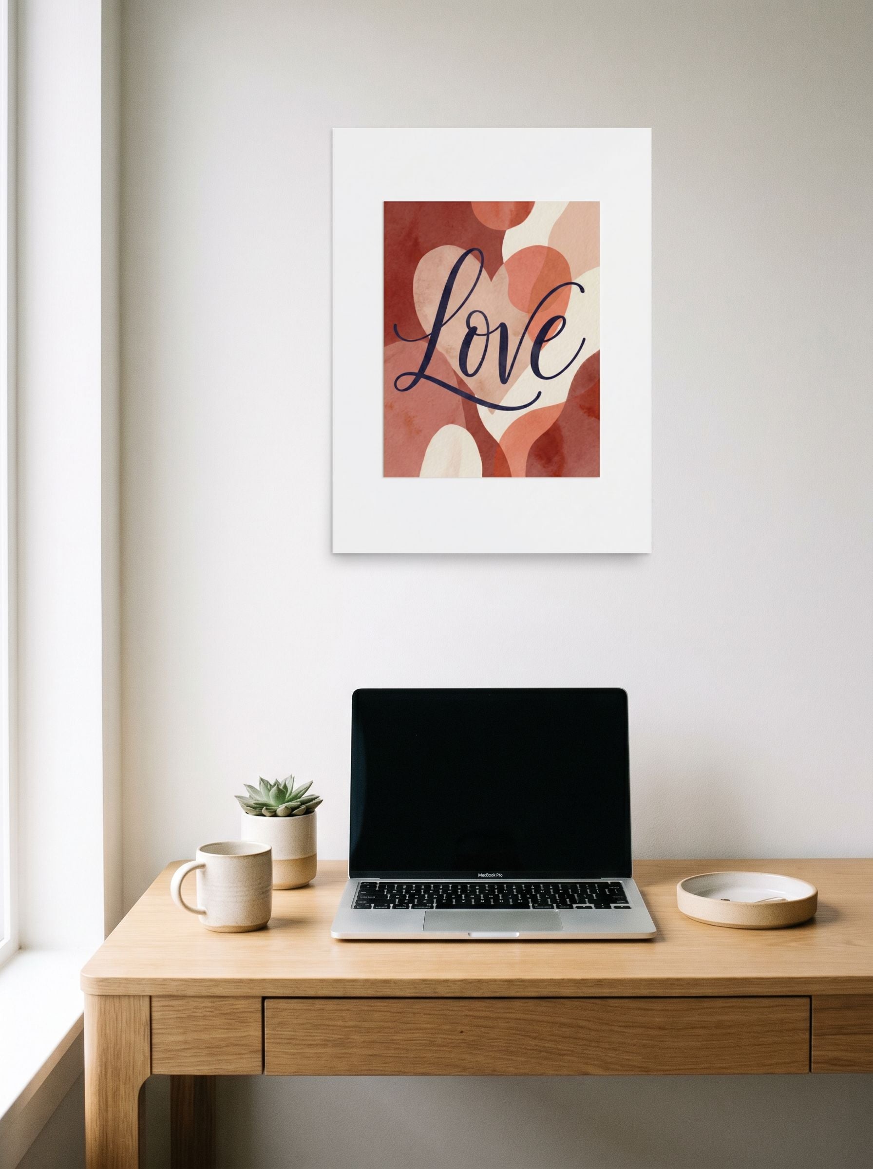 A 18x24 inch unframed paper Abstract art,Minimalism print of 'Painted Affection' hanging above a worktable with a laptop.