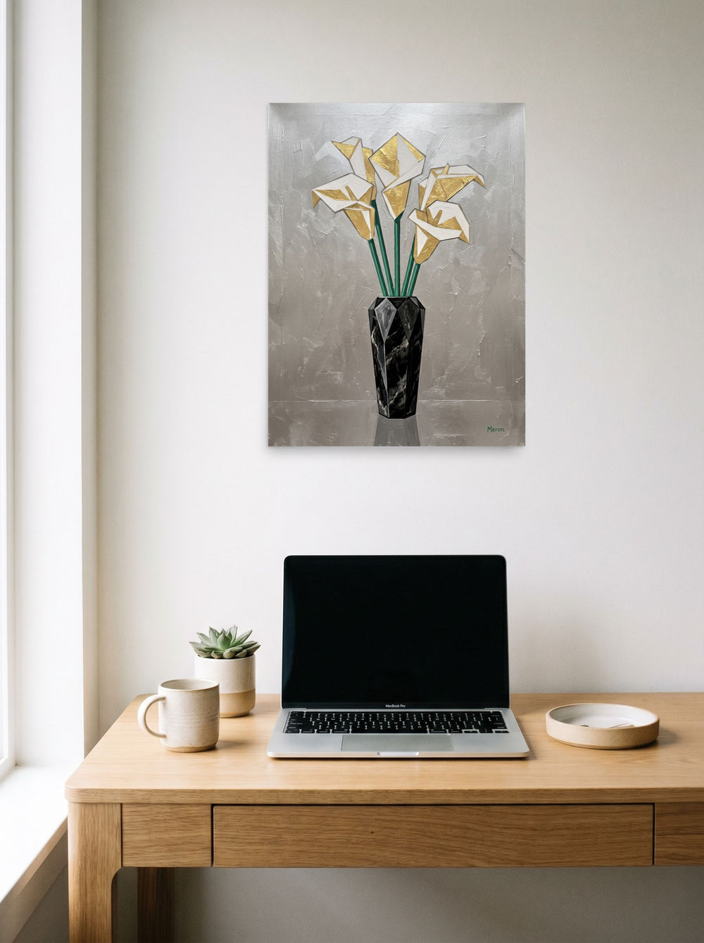 A 18x24 inch unframed paper Art Deco print of 'Deco Calla Lilies' hanging above a worktable with a laptop.