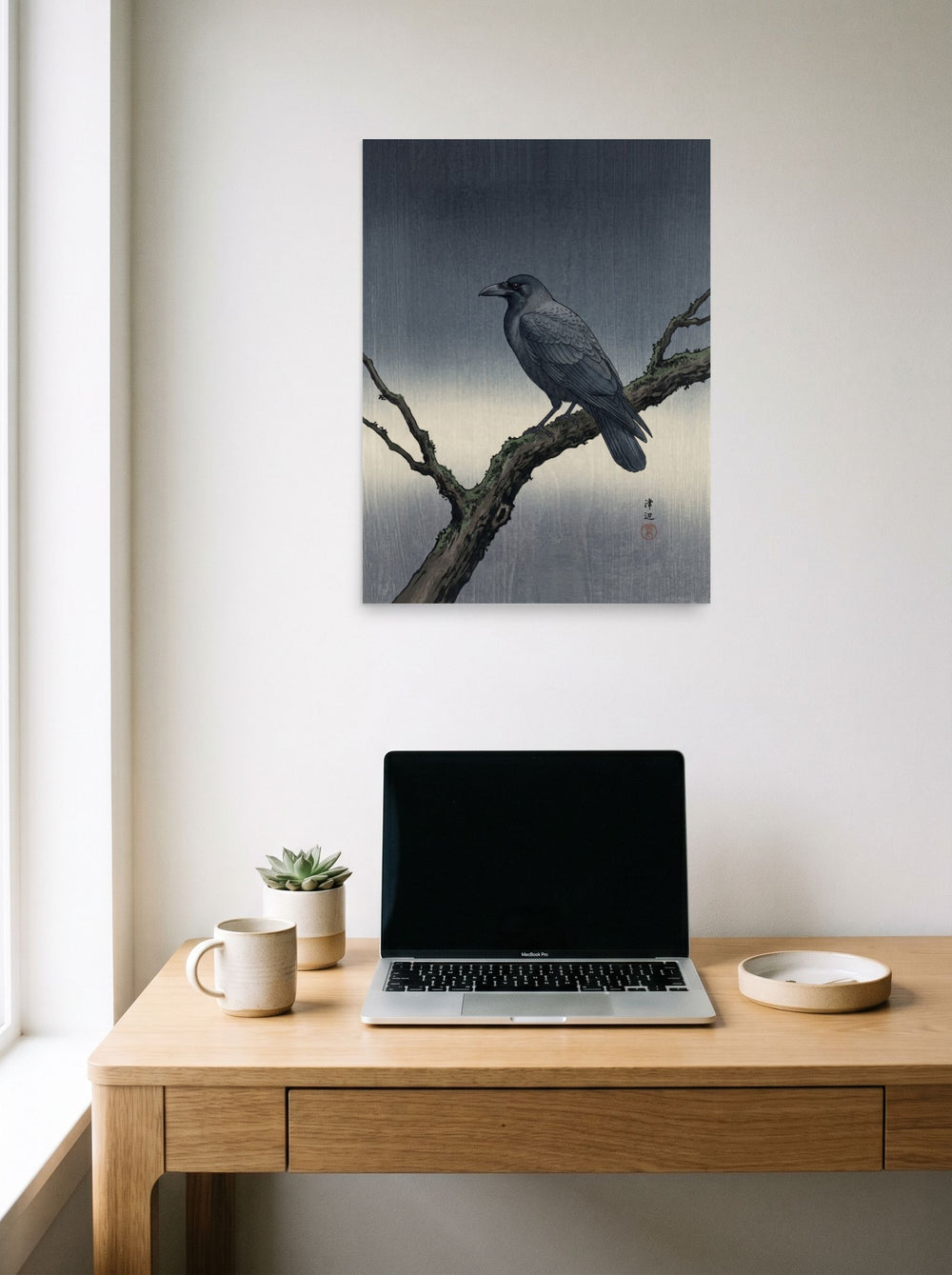 A 18x24 inch unframed paper Shin hanga print of 'Solitary Raven at Dusk' hanging above a worktable with a laptop.