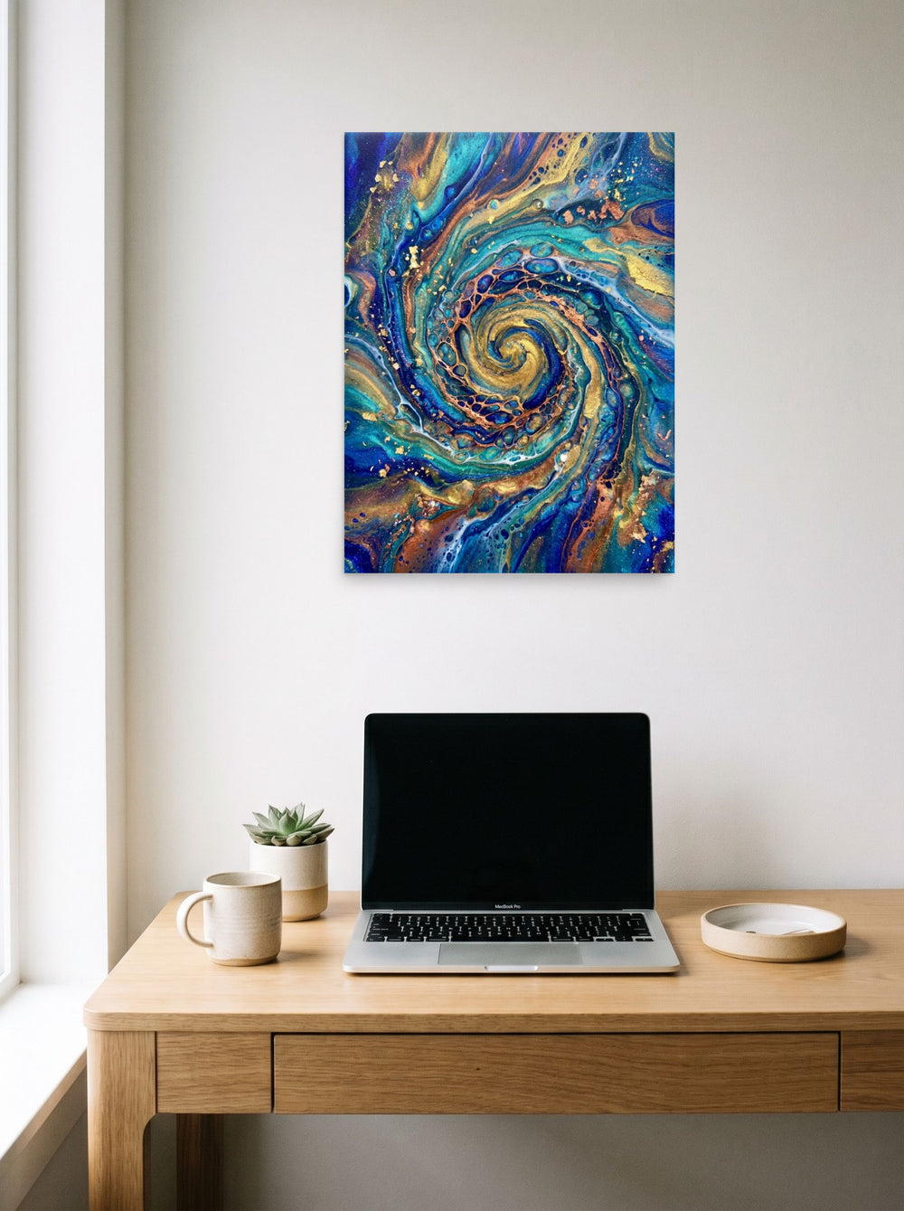 A 18x24 inch unframed paper Abstract art print of 'Golden Vortex' hanging above a worktable with a laptop.