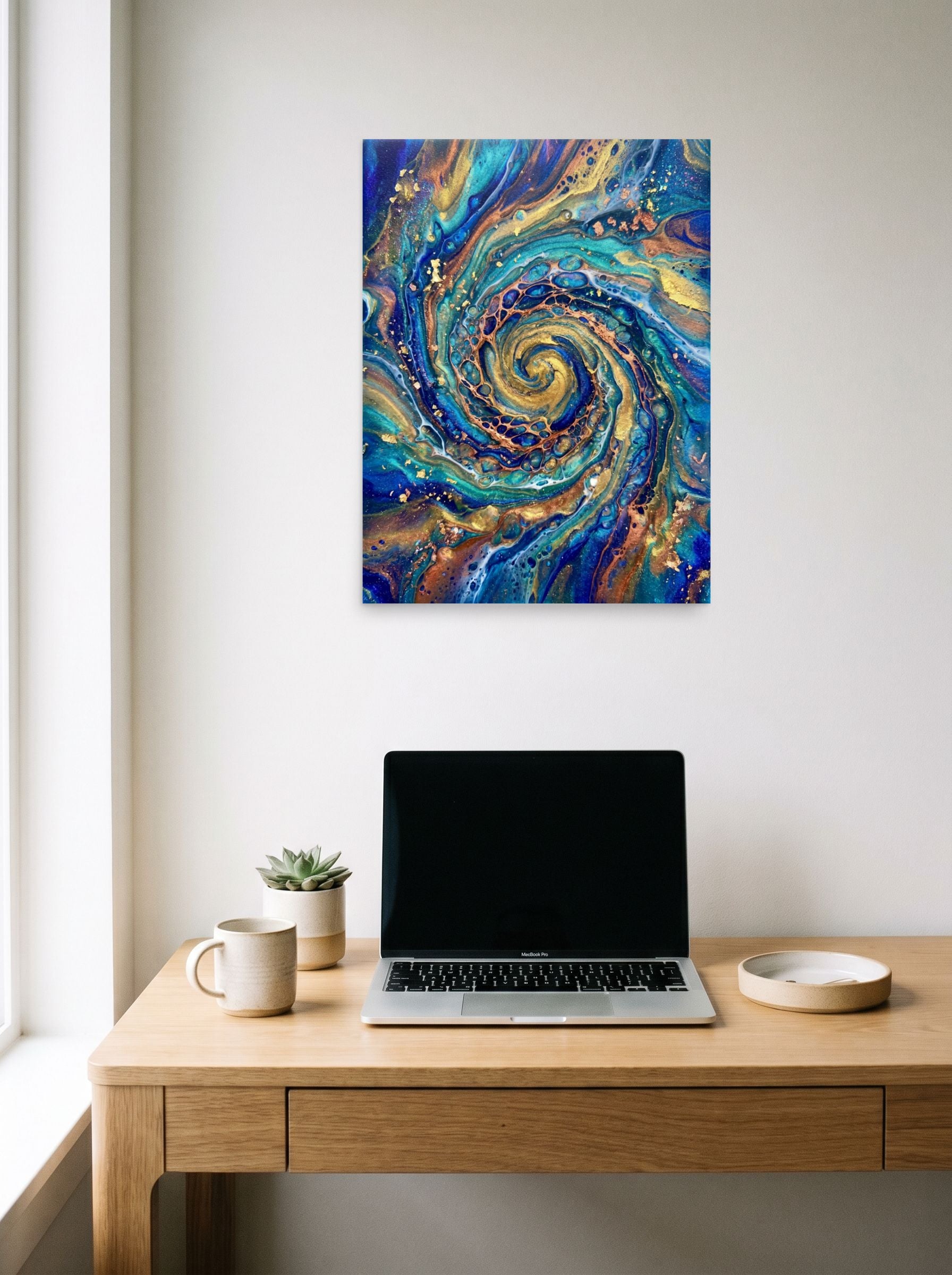 A 18x24 inch unframed paper Abstract art print of 'Golden Vortex' hanging above a worktable with a laptop.