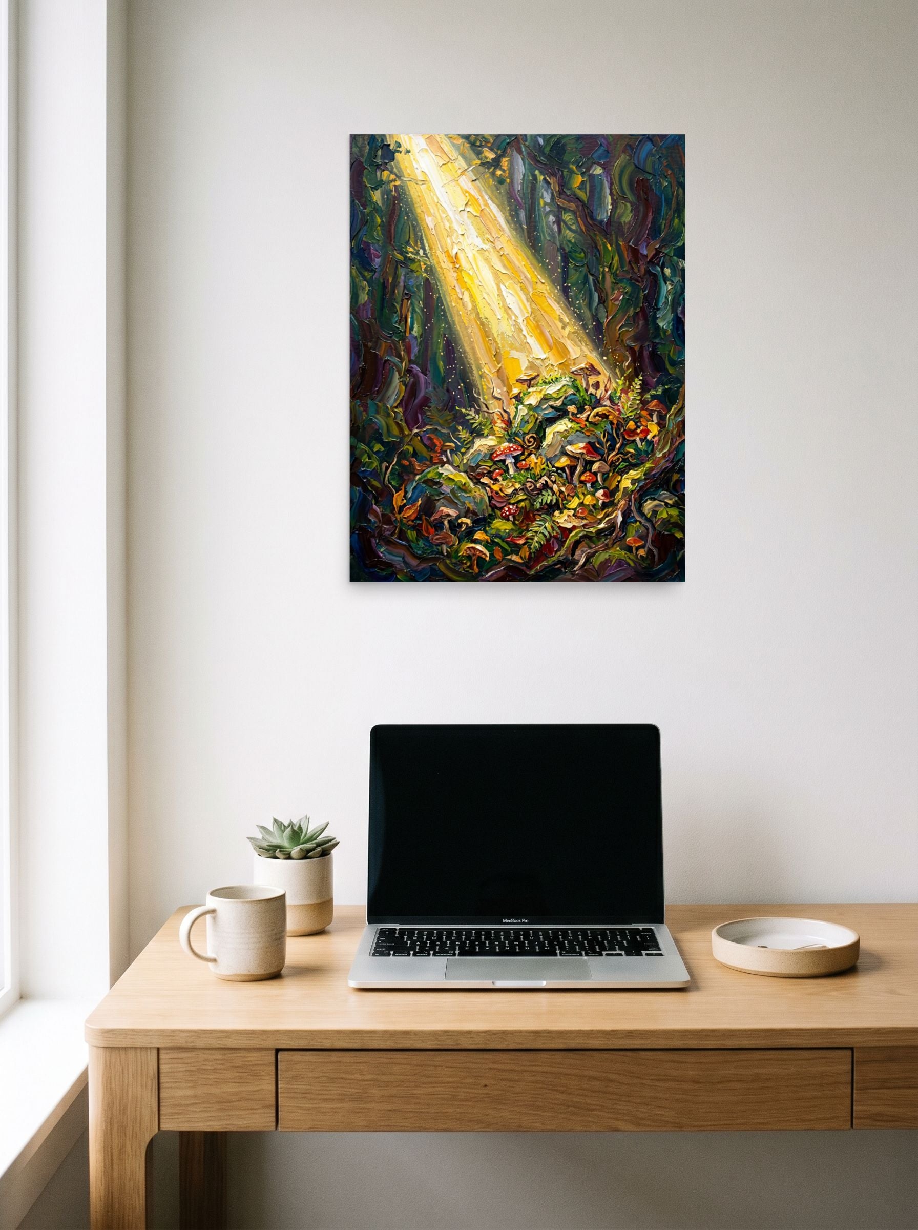 A 18x24 inch unframed paper Impressionism print of 'Forest Illumination' hanging above a worktable with a laptop.