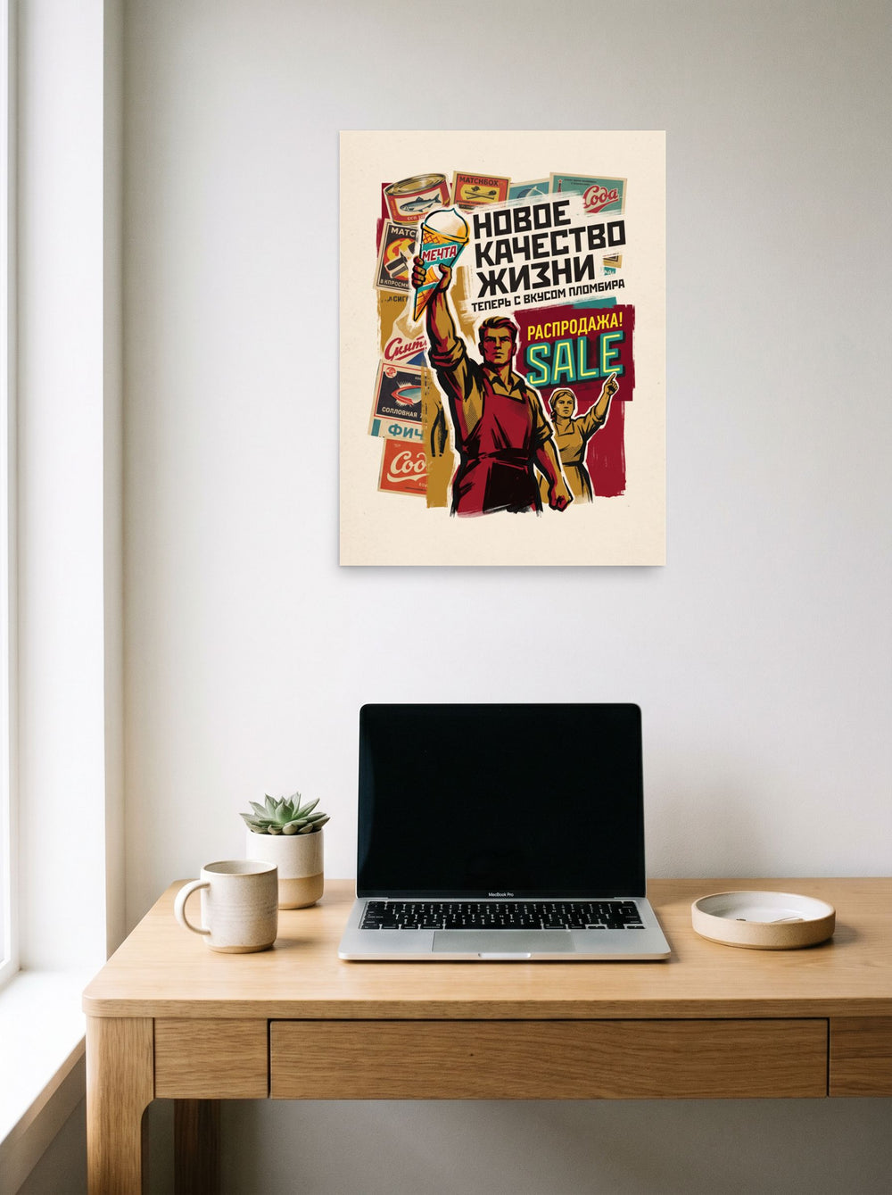 A 18x24 inch unframed paper version of 'New Quality of Life', Pop art wall art, hanging above a worktable with a laptop.