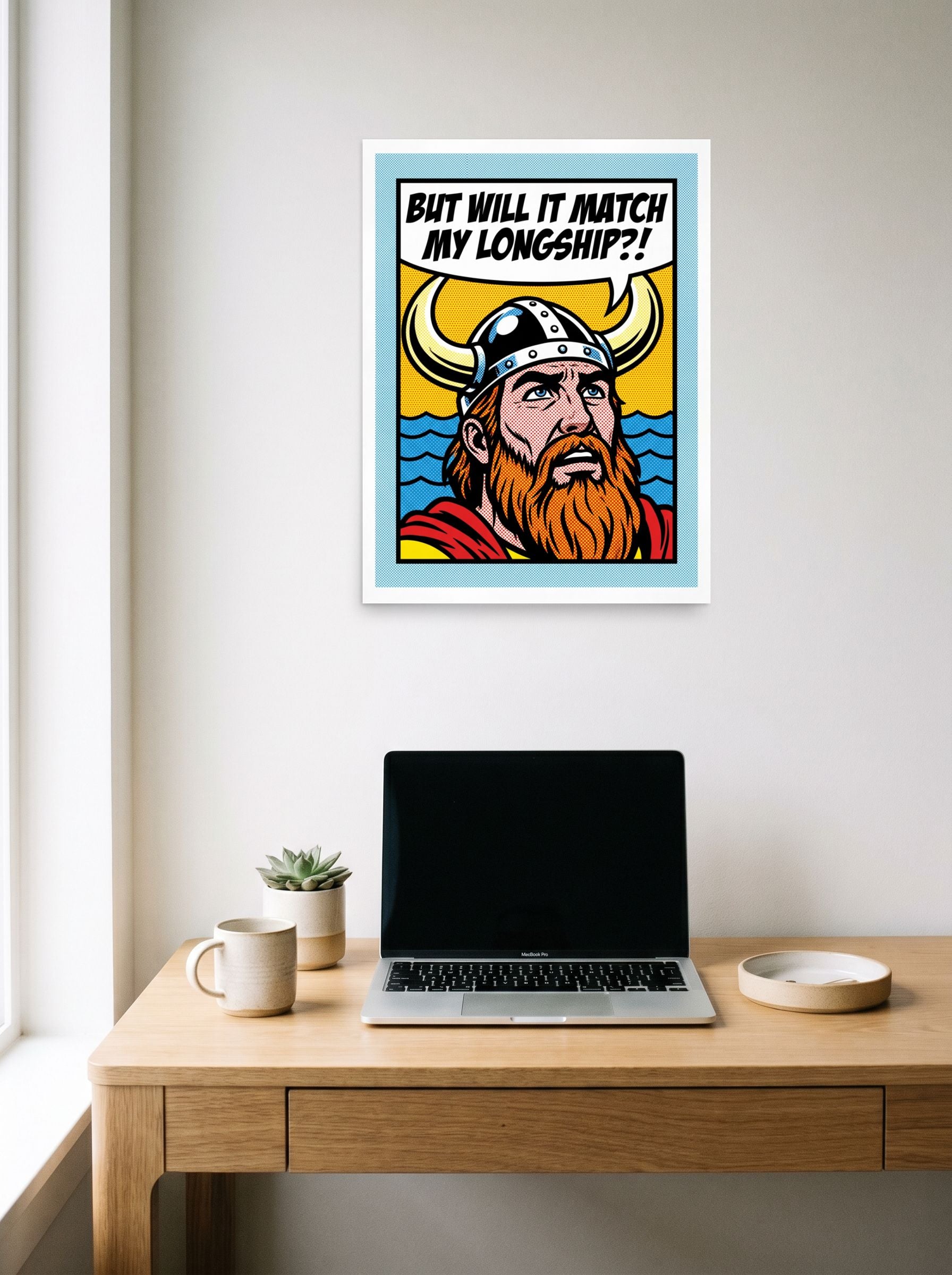 A 18x24 inch unframed paper Pop art print of 'Viking Decor Dilemma' hanging above a worktable with a laptop.