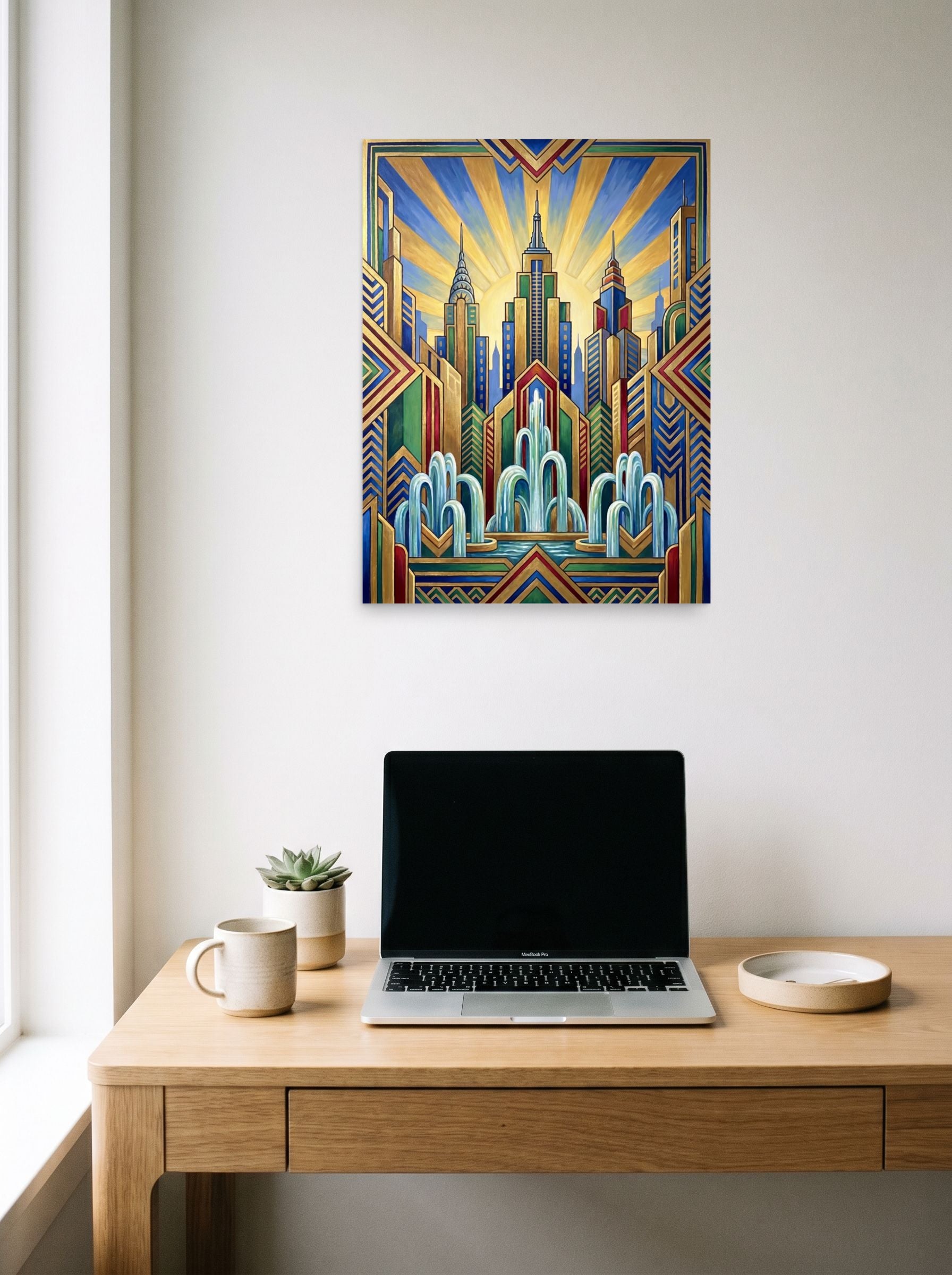 A 18x24 inch unframed paper Art Deco print of 'The Fountain of Progress' hanging above a worktable with a laptop.