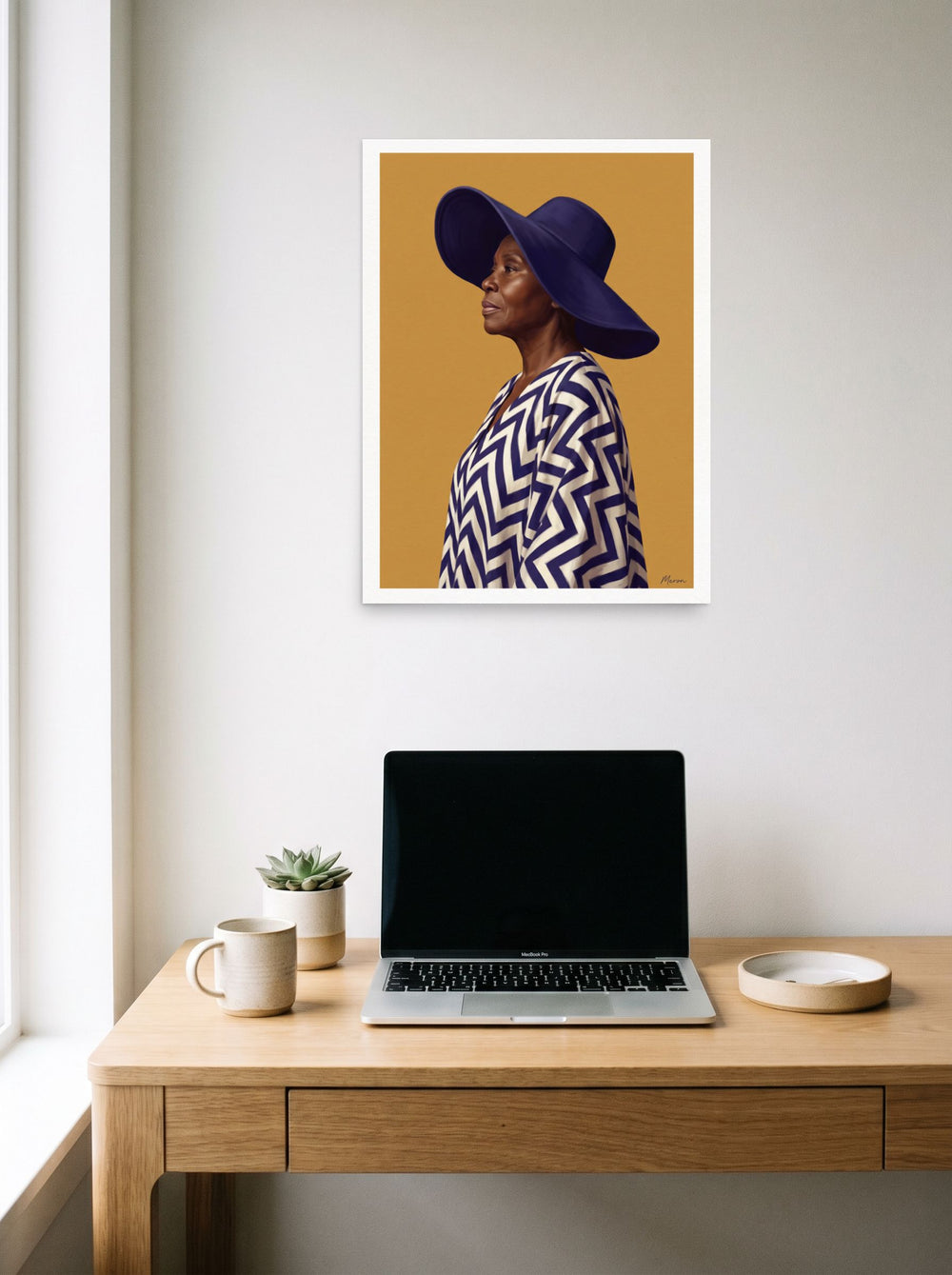 A 18x24 inch unframed paper Realism,Figurative art print of 'Grace in Indigo' hanging above a worktable with a laptop.