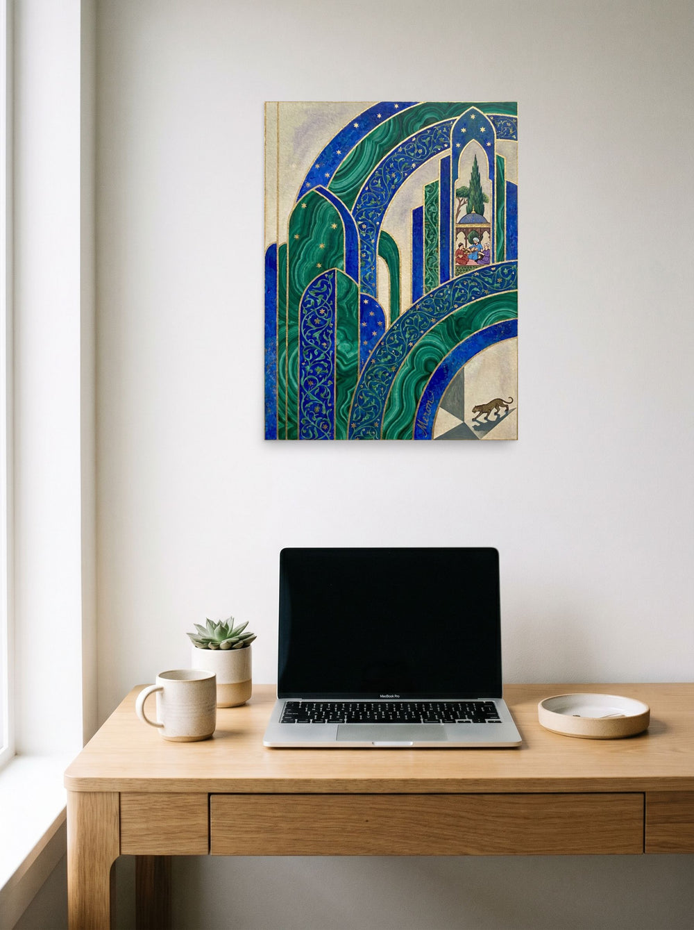 A 18x24 inch unframed paper Art Deco print of 'Malachite Palace' hanging above a worktable with a laptop.
