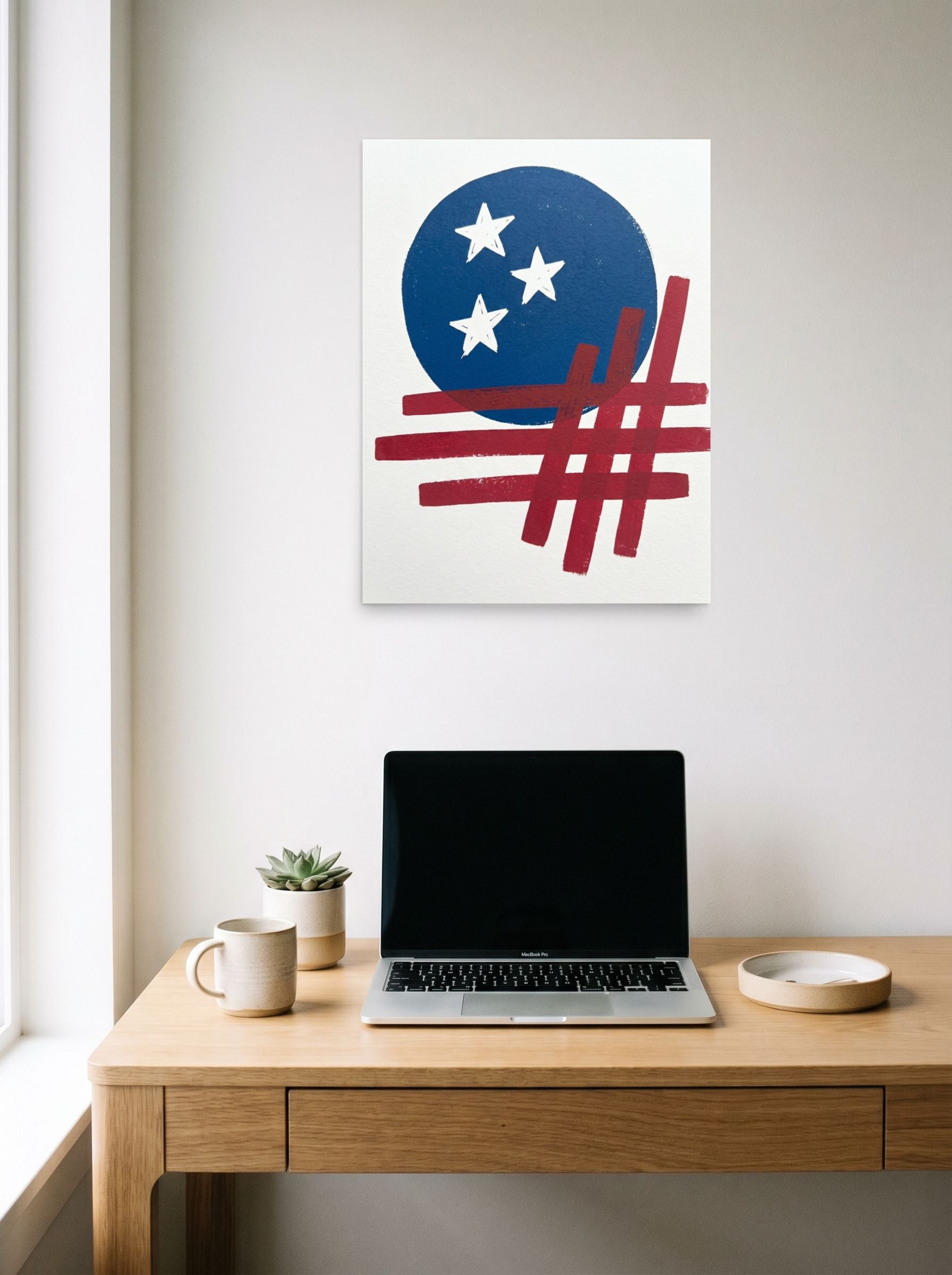 A 18x24 inch unframed paper Abstract art print of 'Patriotic Abstraction' hanging above a worktable with a laptop.