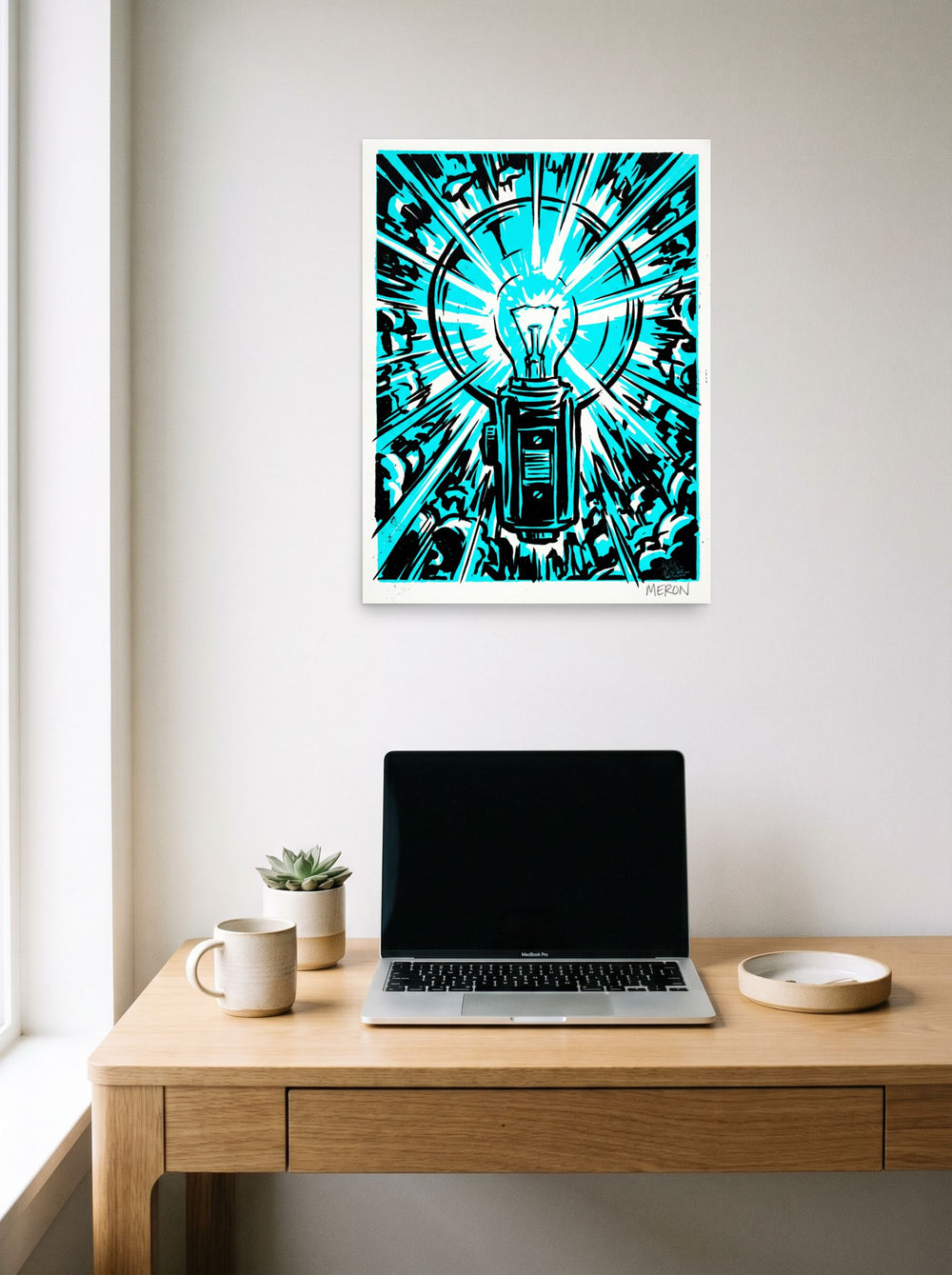 A 18x24 inch unframed paper Pop art print of 'Cyan Eureka' hanging above a worktable with a laptop.