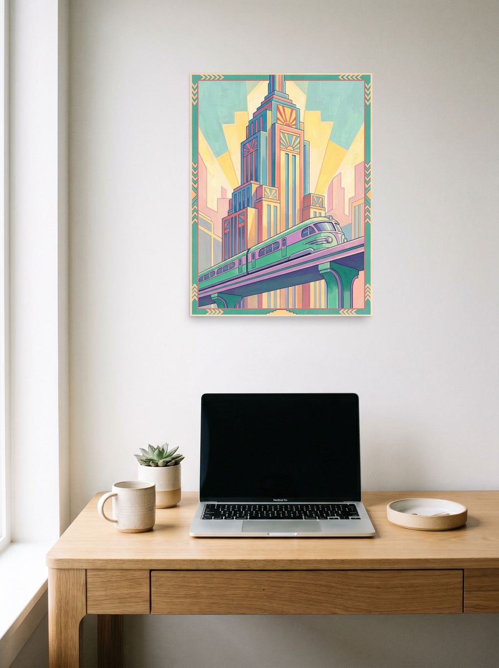 A 18x24 inch unframed paper Art Deco print of 'The Pastel Express' hanging above a worktable with a laptop.