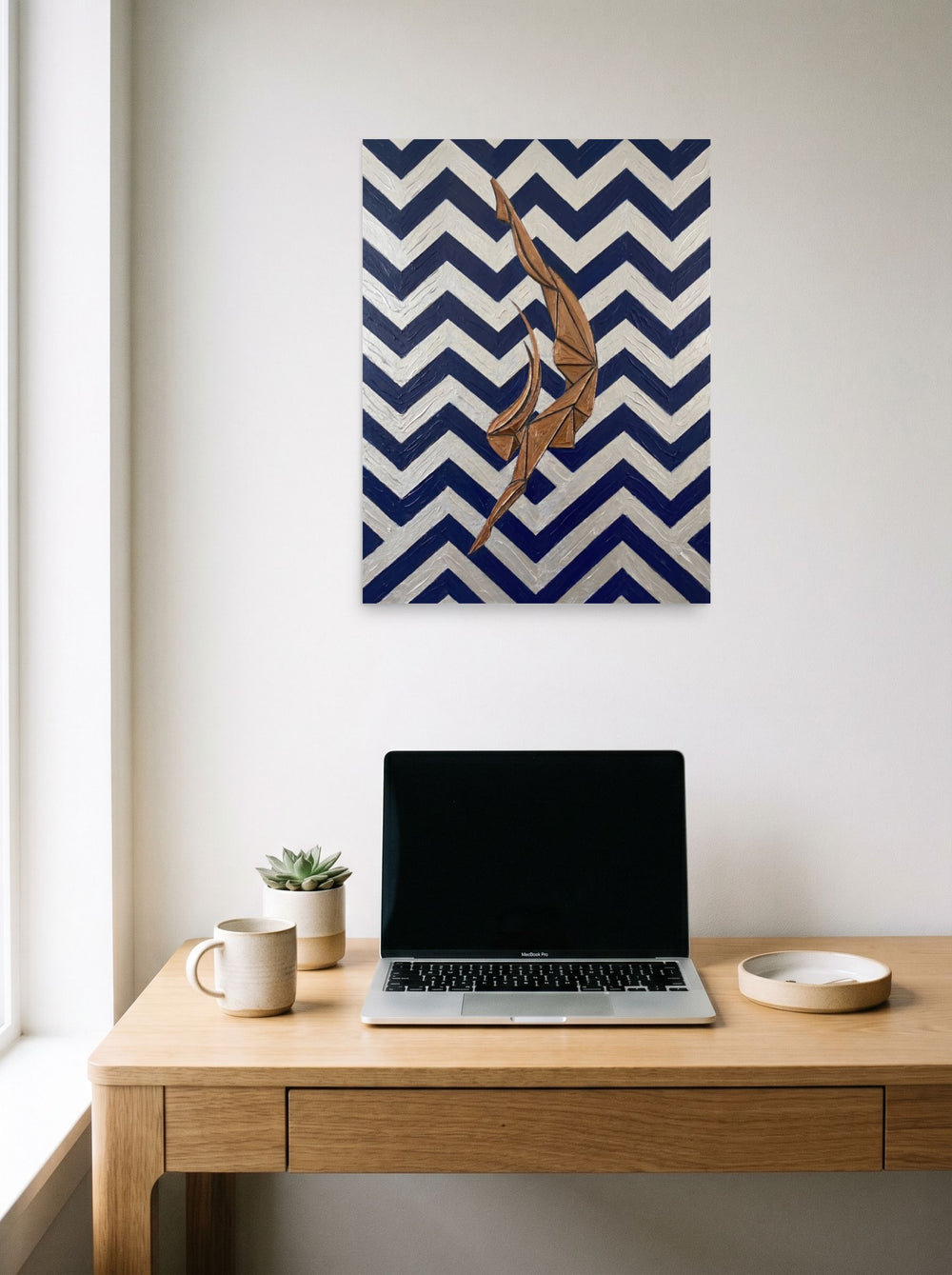 A 18x24 inch unframed paper Art Deco print of 'The Deco Diver' hanging above a worktable with a laptop.