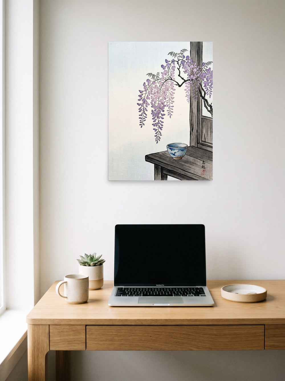 A 18x24 inch unframed paper Shin hanga print of 'Wisteria and Tea' hanging above a worktable with a laptop.