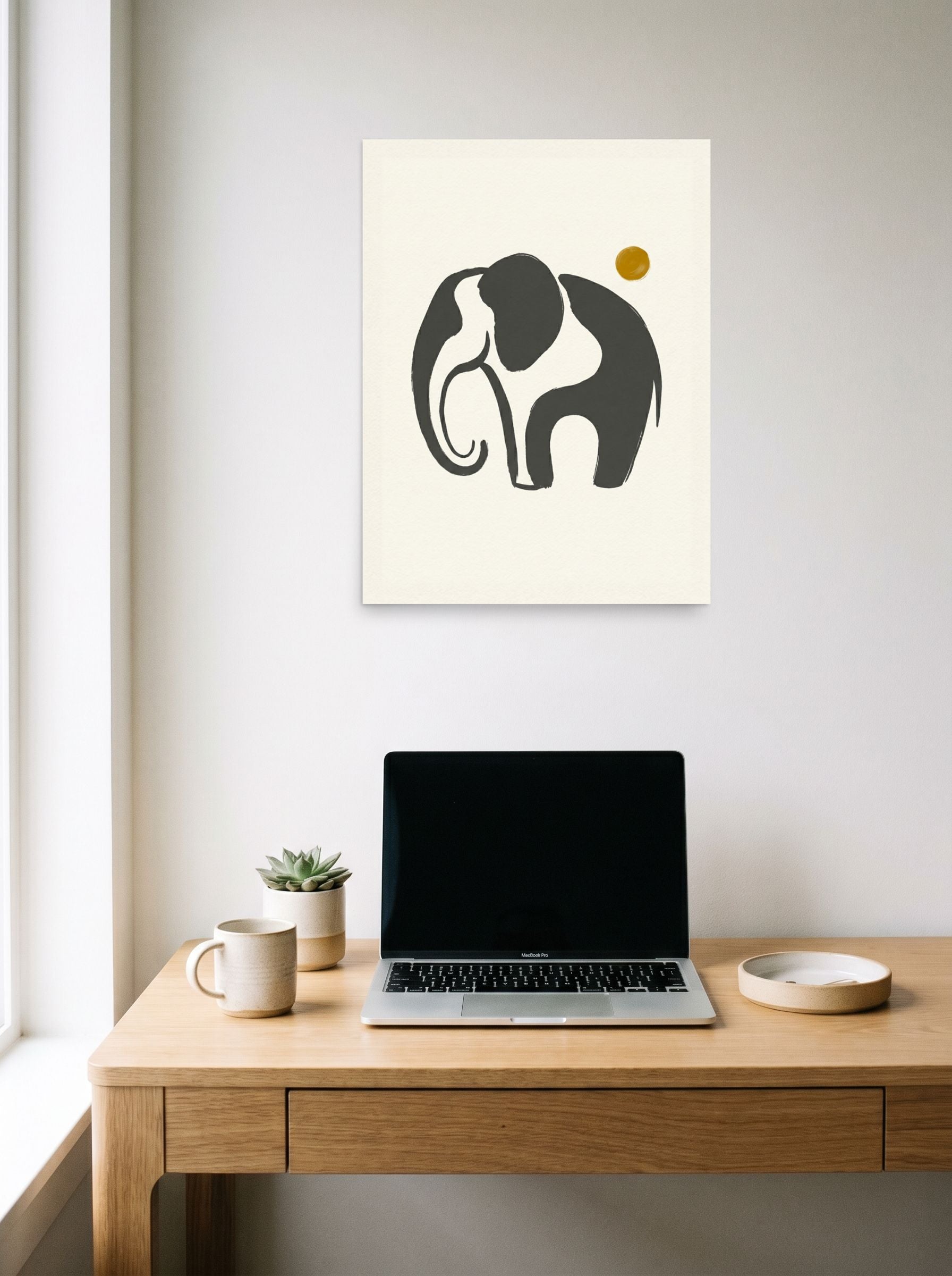 A 18x24 inch unframed paper Minimalism print of 'Elephant under the Golden Sun' hanging above a worktable with a laptop.
