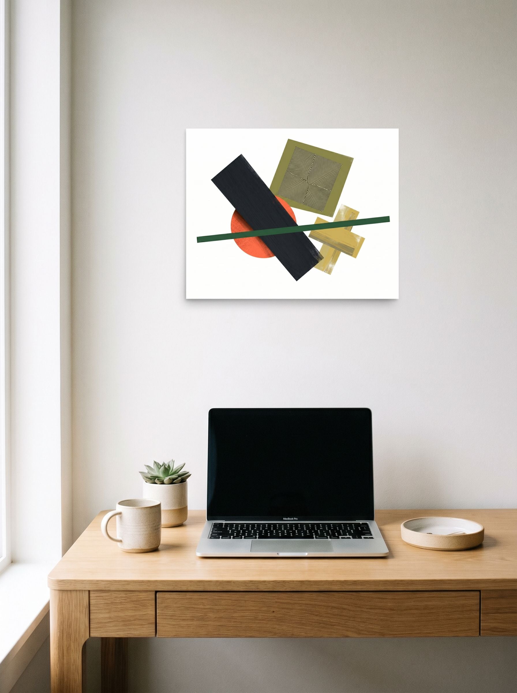 A 20x16 inch unframed paper Suprematism print of 'The Geometry of Sound' hanging above a worktable with a laptop.