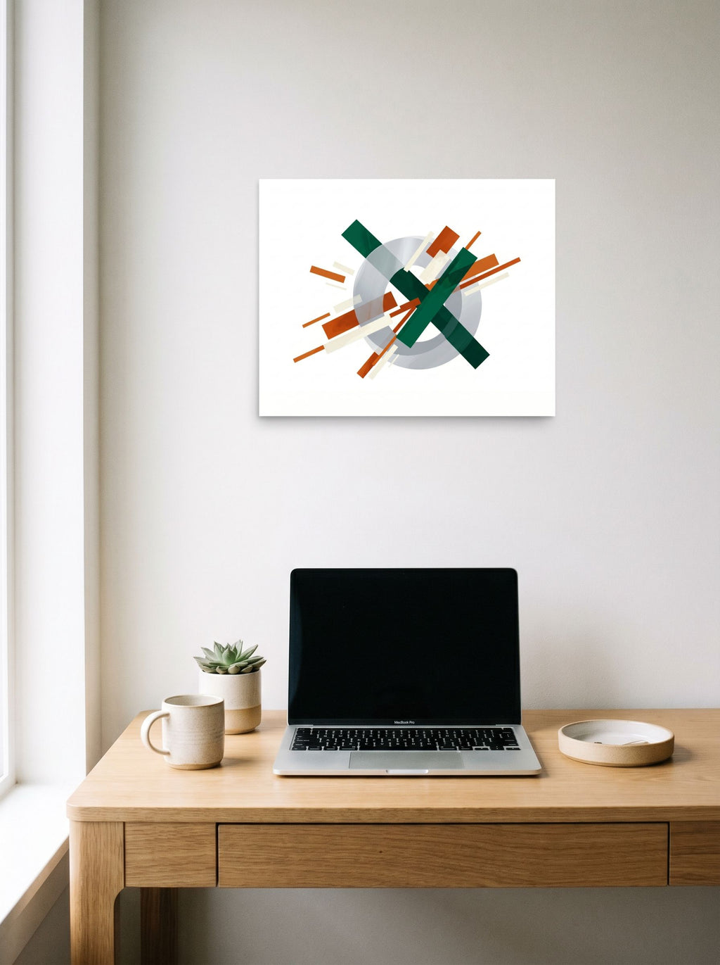 A 20x16 inch unframed paper Suprematism print of 'Intersecting Perspectives' hanging above a worktable with a laptop.