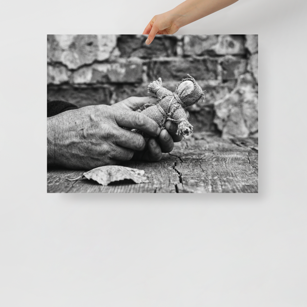 'The Keeper of Memories' — a Art photography print. A black and white photograph of an older person's hands holding a small burlap doll over a cracked wooden table, an atmospheric piece for a Library.