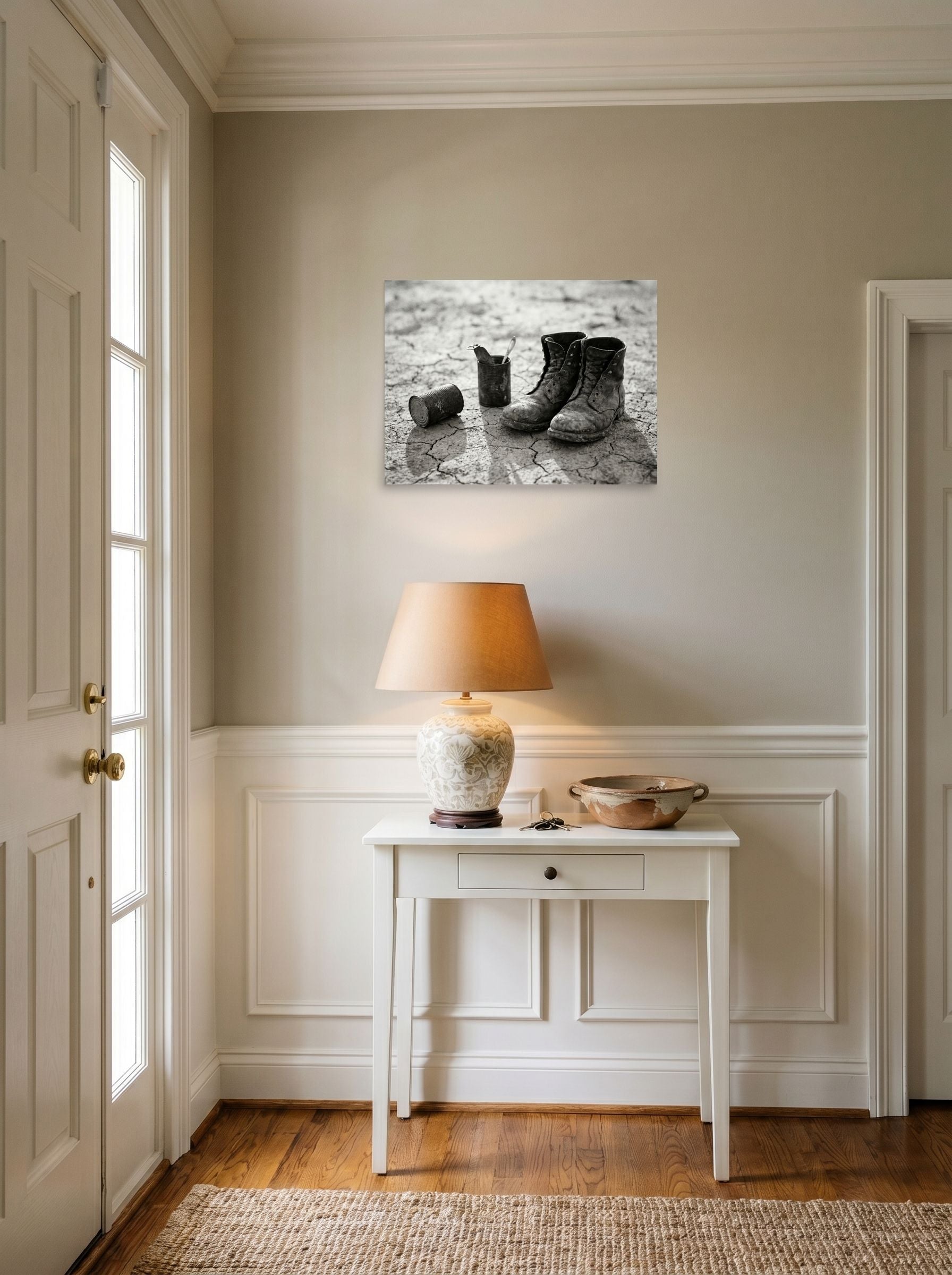 A 24x18 inch unframed paper American realism print of 'The Drifter's Boots' hanging in an entryway near a console.