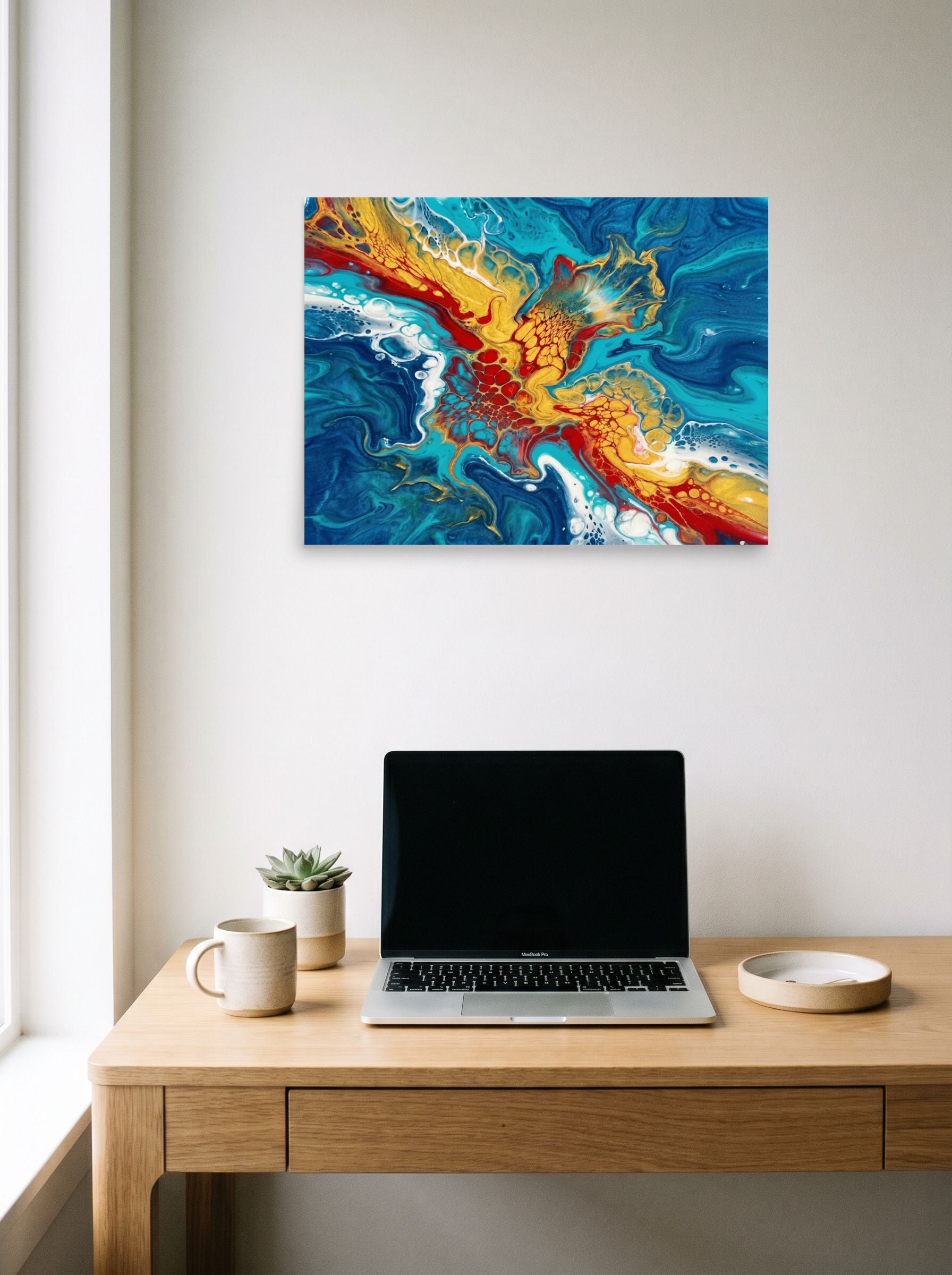 A 24x18 inch unframed paper Abstract art print of 'Crimson Splash' hanging above a worktable with a laptop.