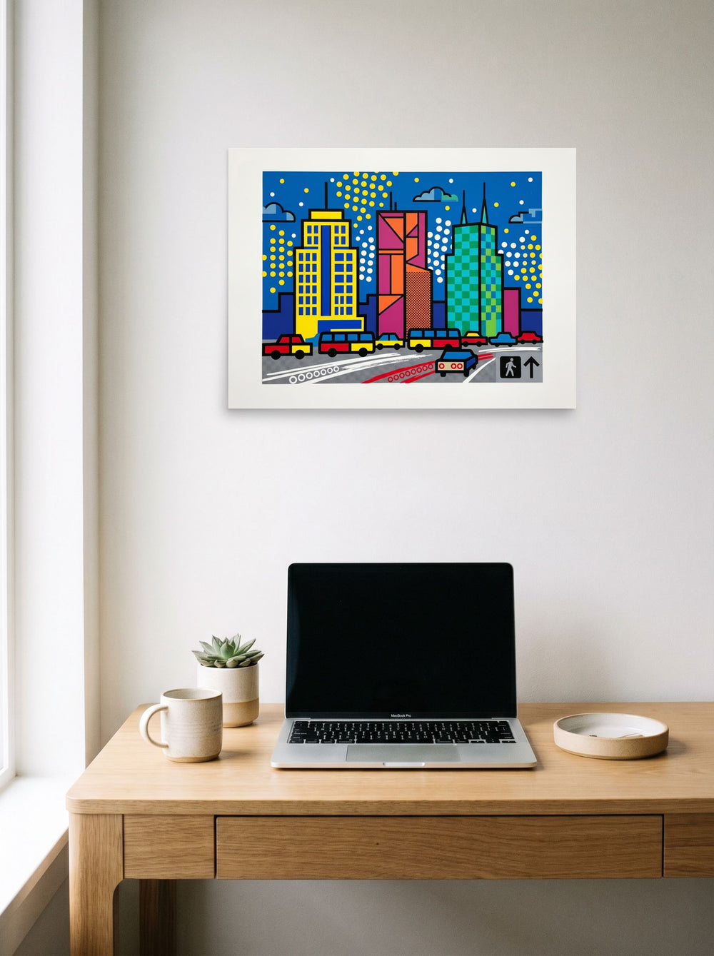 A 24x18 inch unframed paper Pop art print of 'City Commute Pop' hanging above a worktable with a laptop.