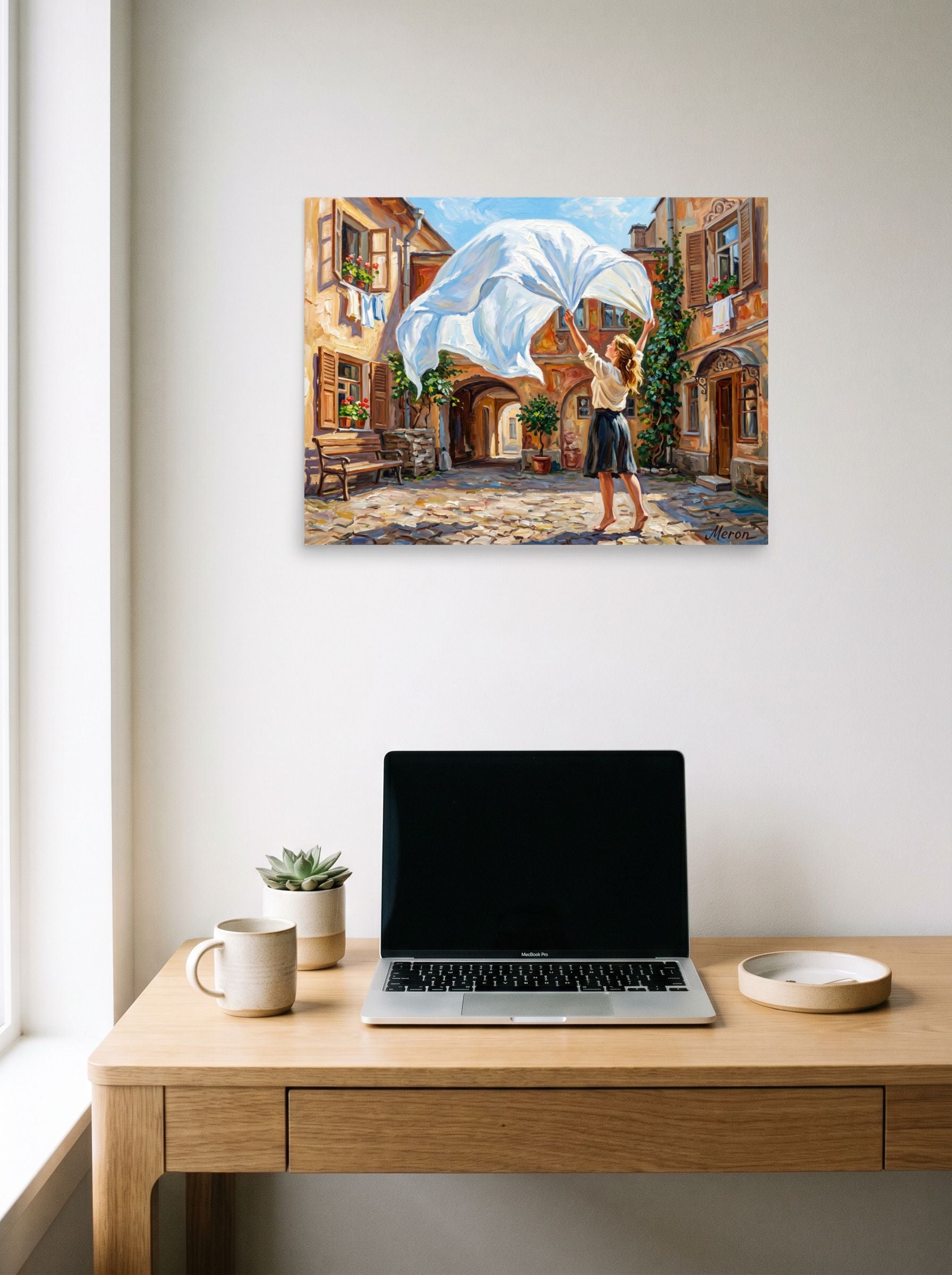 A 24x18 inch unframed paper Impressionism print of 'The White Sheet' hanging above a worktable with a laptop.