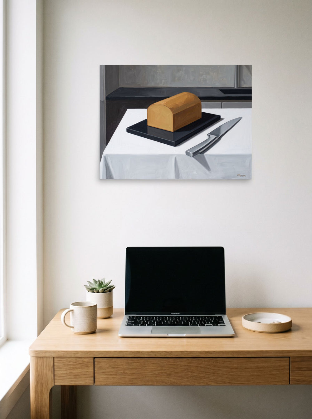 A 24x18 inch unframed paper Art Deco print of 'The Morning Loaf' hanging above a worktable with a laptop.