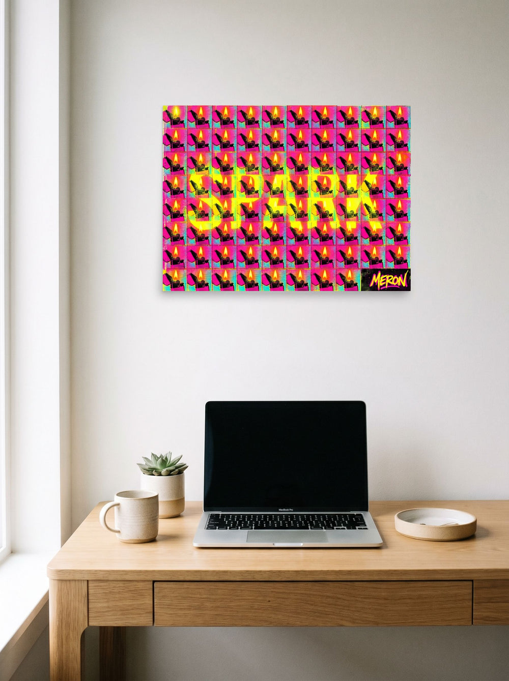 A 24x18 inch unframed paper Pop art print of 'Magenta Spark Grid' hanging above a worktable with a laptop.