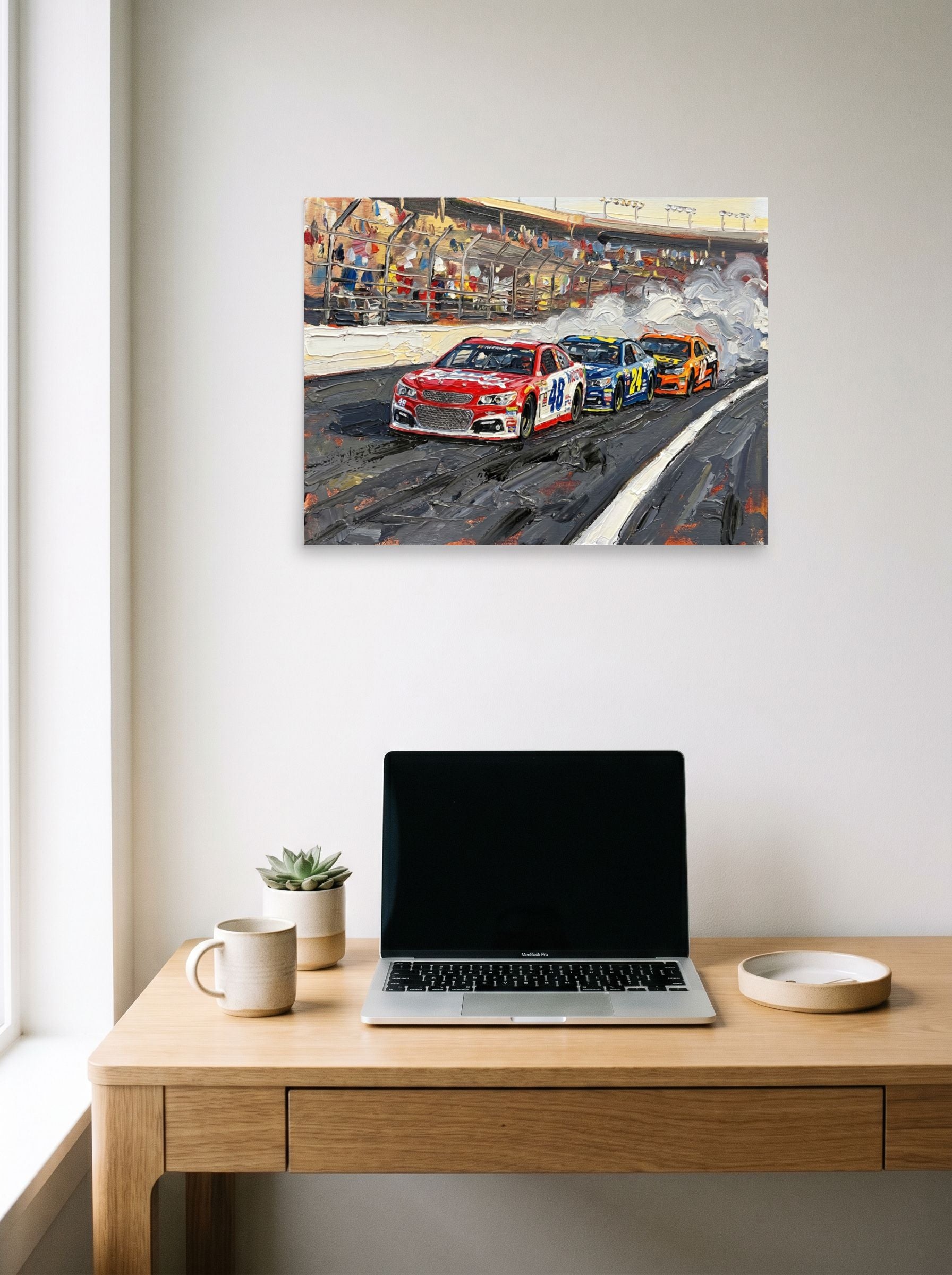 A 24x18 inch unframed paper Expressionism print of 'Thunder on the Track' hanging above a worktable with a laptop.