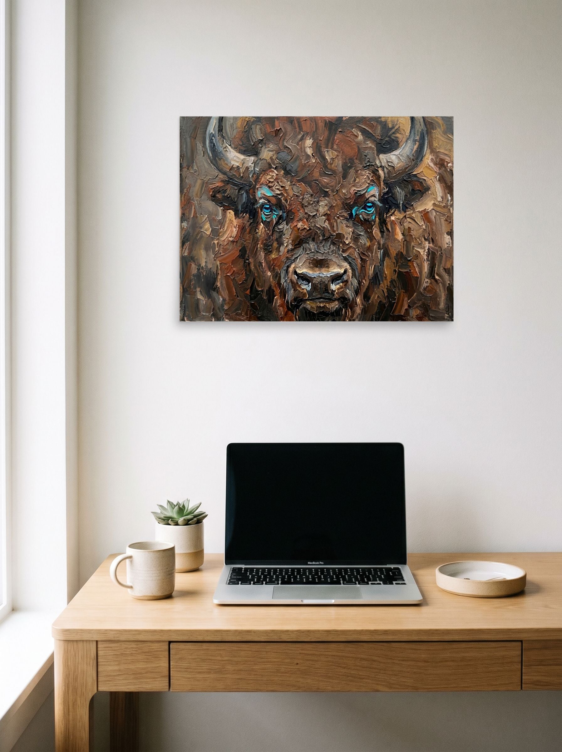 A 24x18 inch unframed paper Realism print of 'Gaze of the Plains' hanging above a worktable with a laptop.