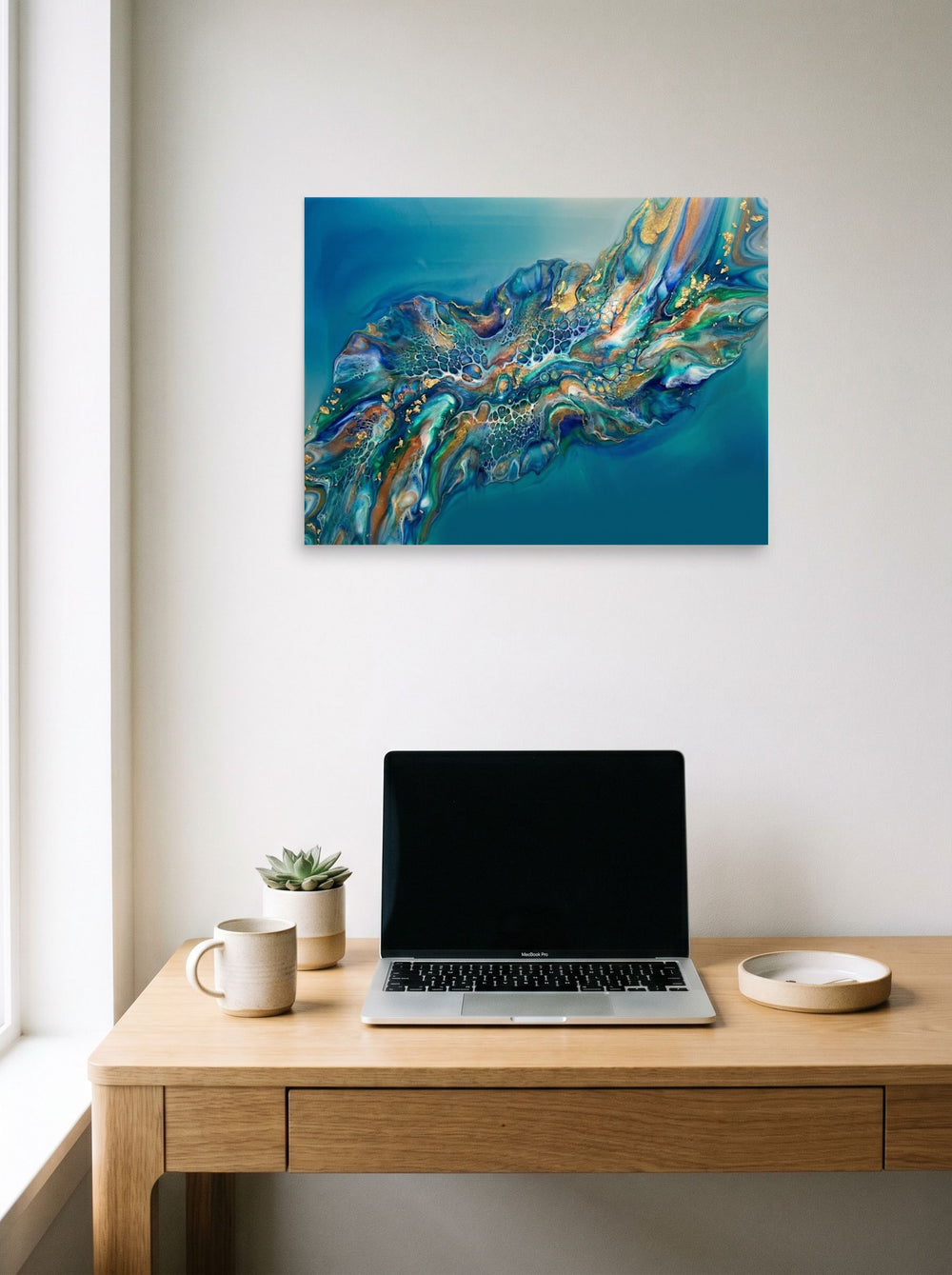 A 24x18 inch unframed paper Abstract art print of 'Teal Nebula' hanging above a worktable with a laptop.
