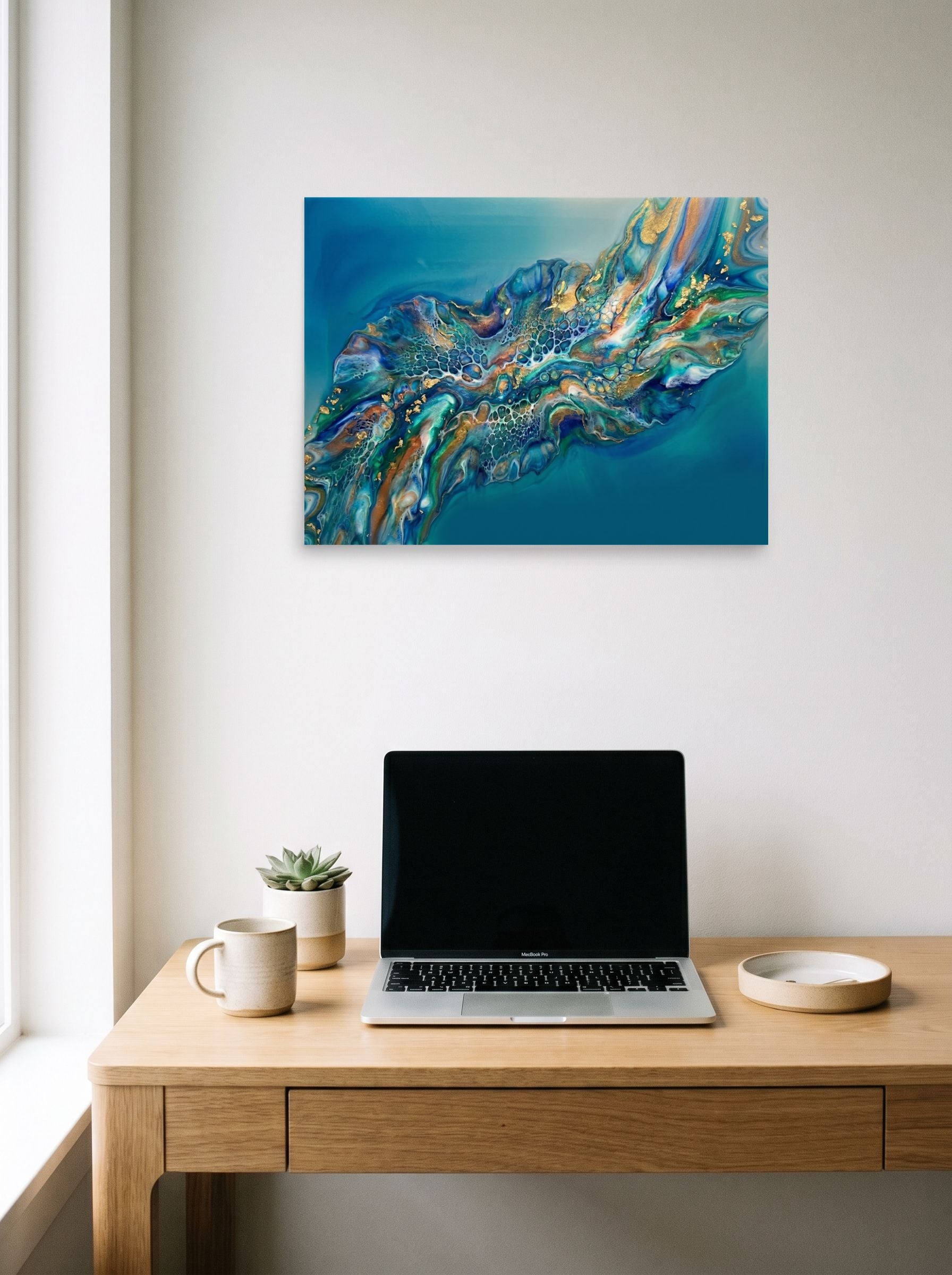 A 24x18 inch unframed paper Abstract art print of 'Teal Nebula' hanging above a worktable with a laptop.