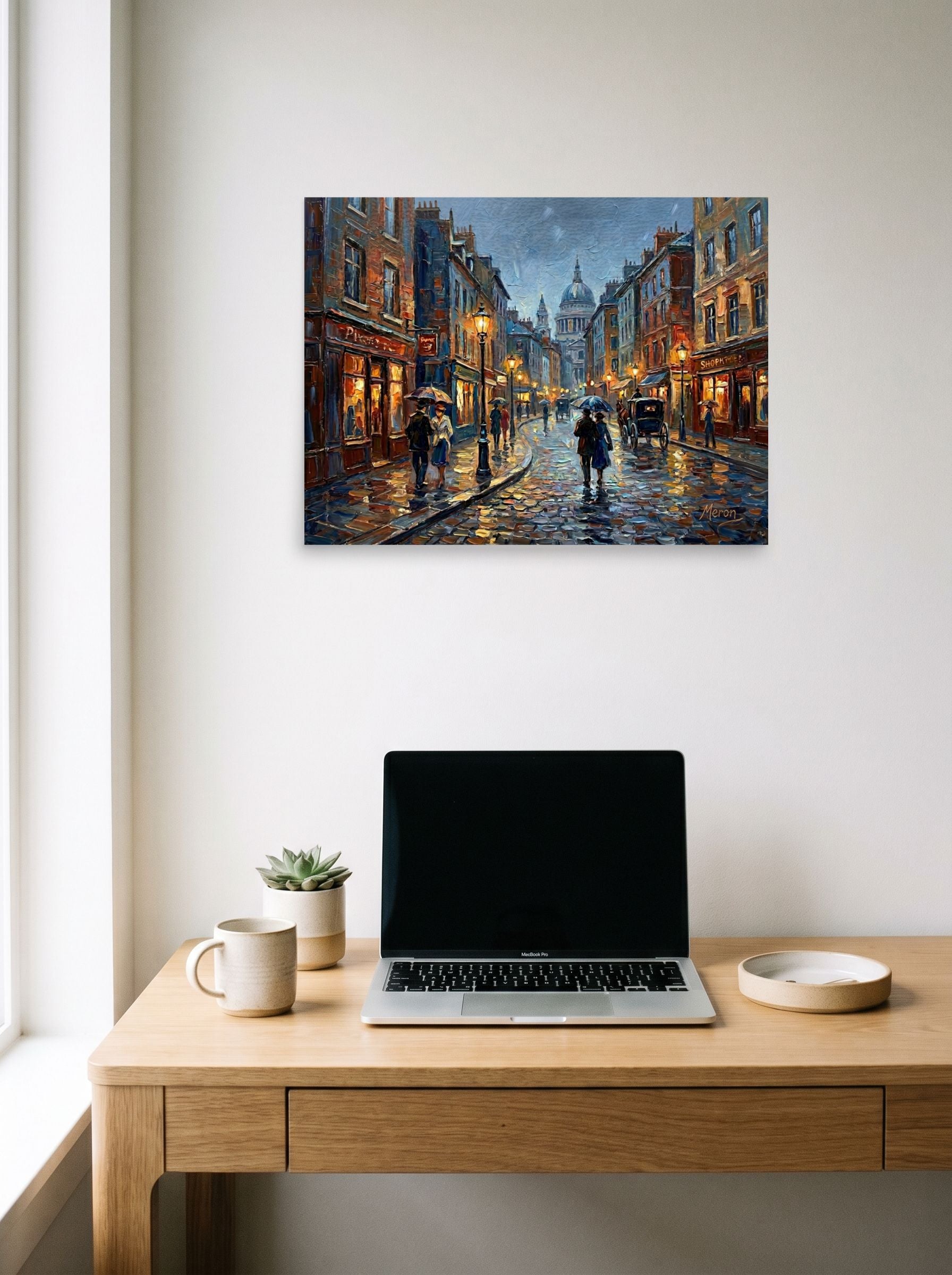 A 24x18 inch unframed paper Impressionism print of 'Evening Rain in the City' hanging above a worktable with a laptop.