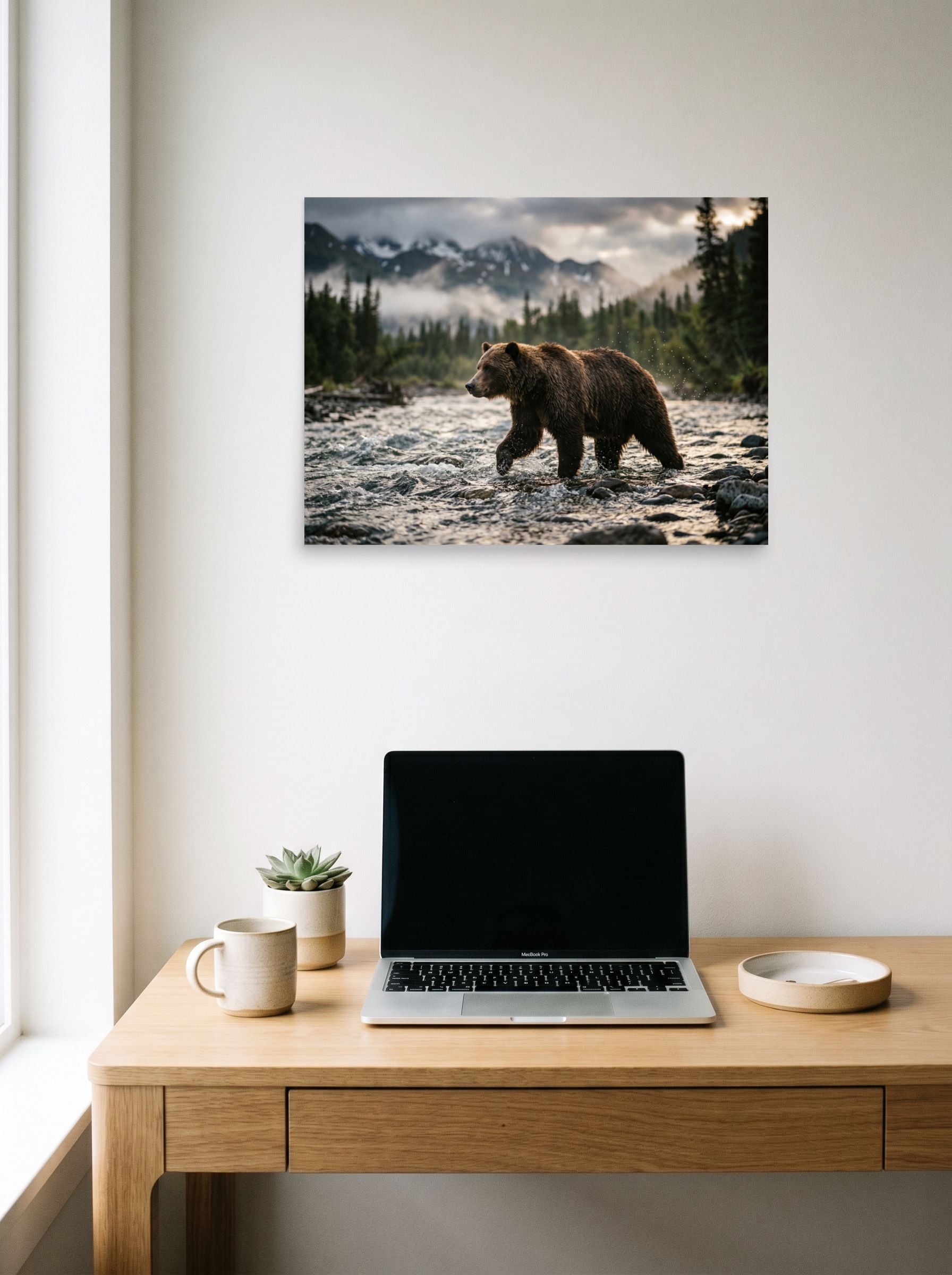 A 24x18 inch unframed paper Art photography print of 'River Crossing' hanging above a worktable with a laptop.
