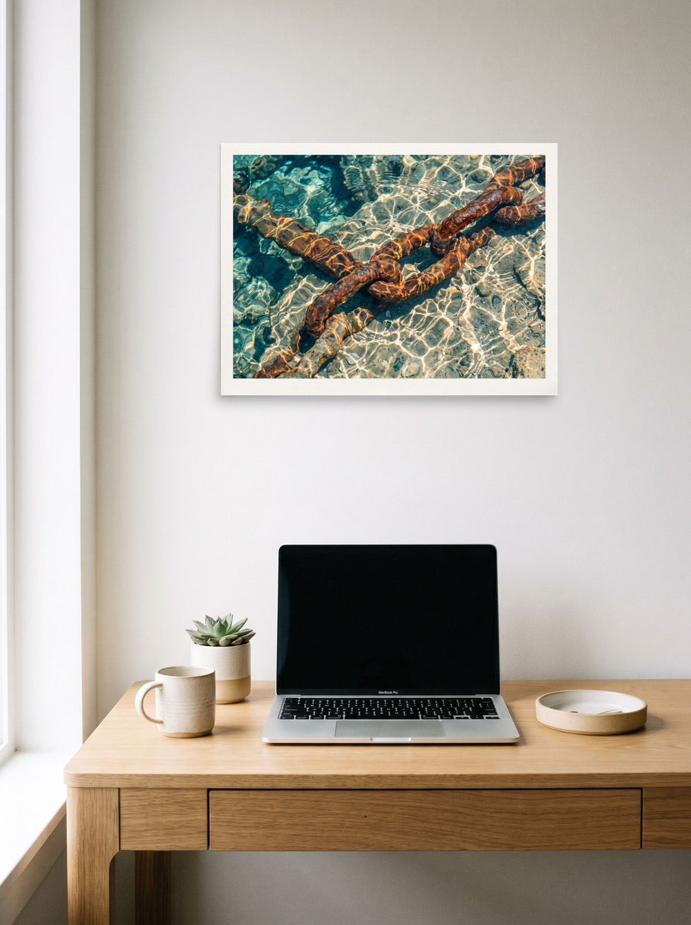 A 24x18 inch unframed paper Art photography print of 'Sunken Mooring Chain' hanging above a worktable with a laptop.