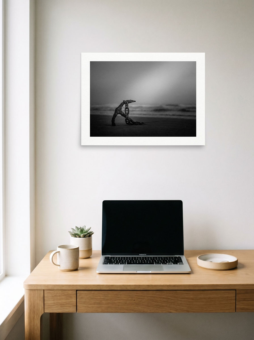 A 24x18 inch unframed paper Art photography print of 'The Old Anchor' hanging above a worktable with a laptop.