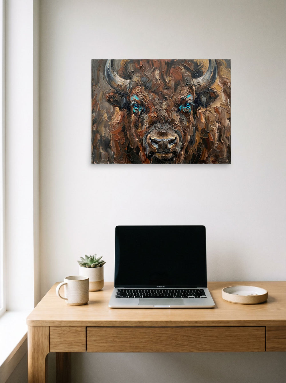 A 24x18 inch unframed paper Realism print of 'Gaze of the Plains' hanging above a worktable with a laptop.
