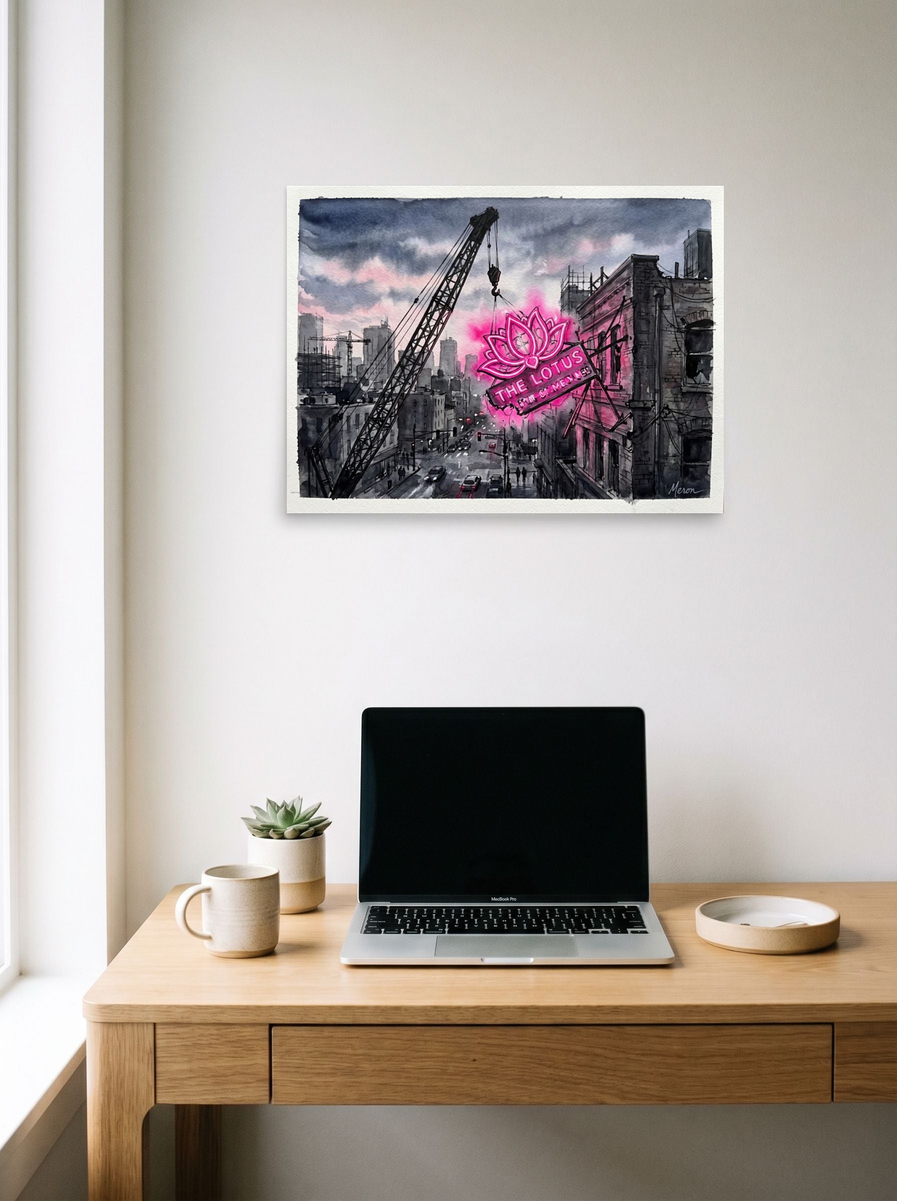 A 24x18 inch unframed paper Realism,Street art print of 'The Lotus Sign' hanging above a worktable with a laptop.